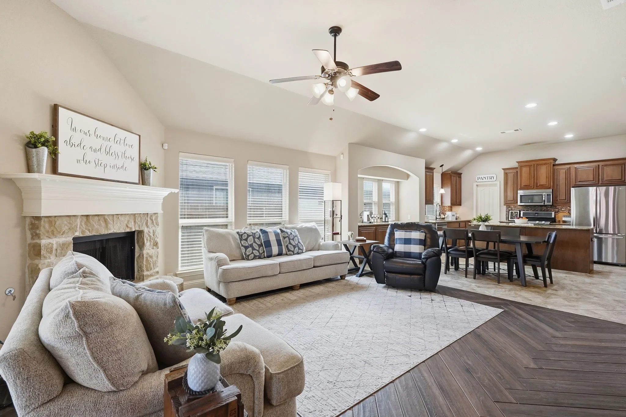 Vaulted ceilings, a stone-surround fireplace with a mantel, and dark wood-finish flooring