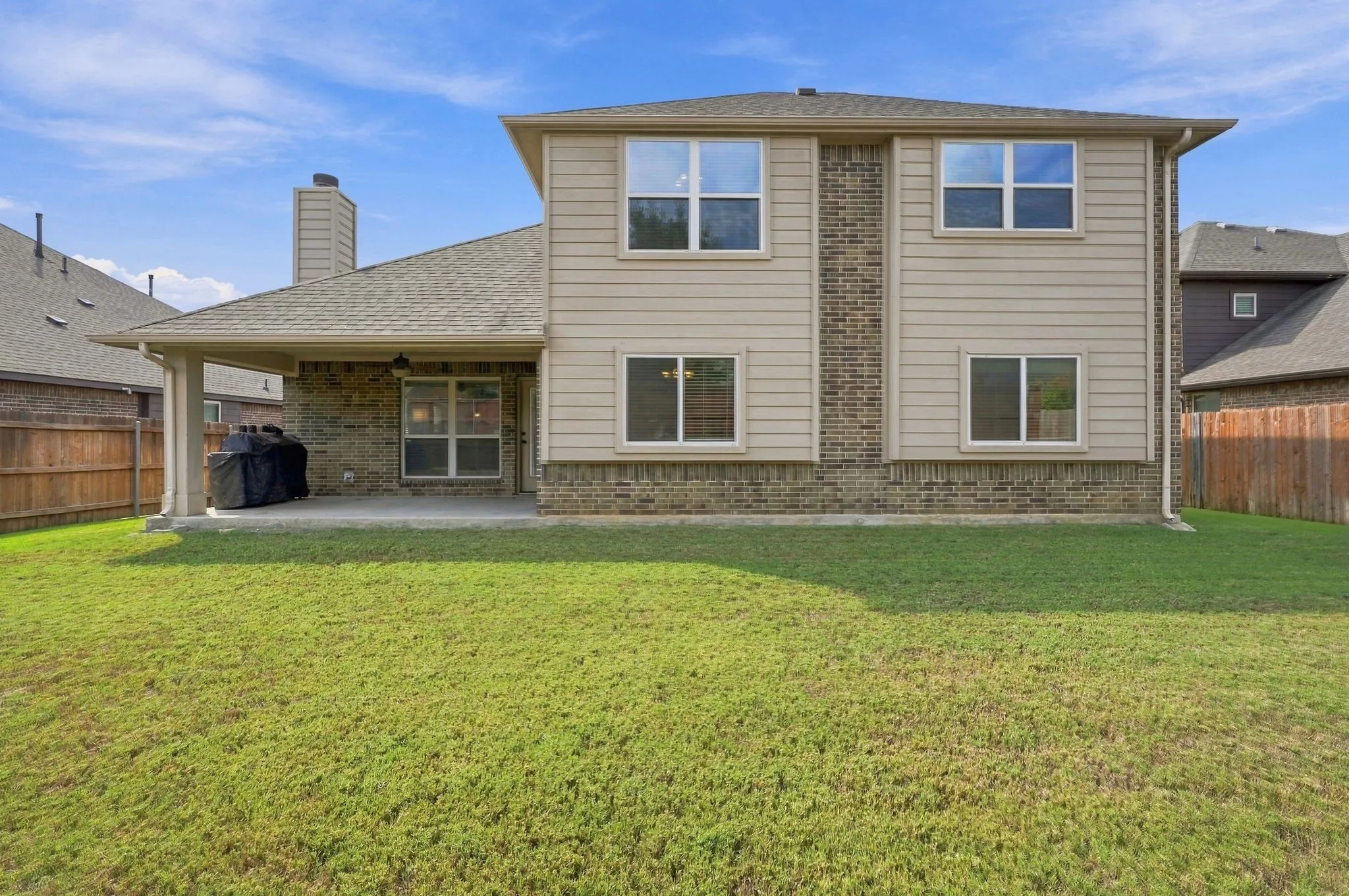 Expansive backyard featuring a manicured lawn & covered patio