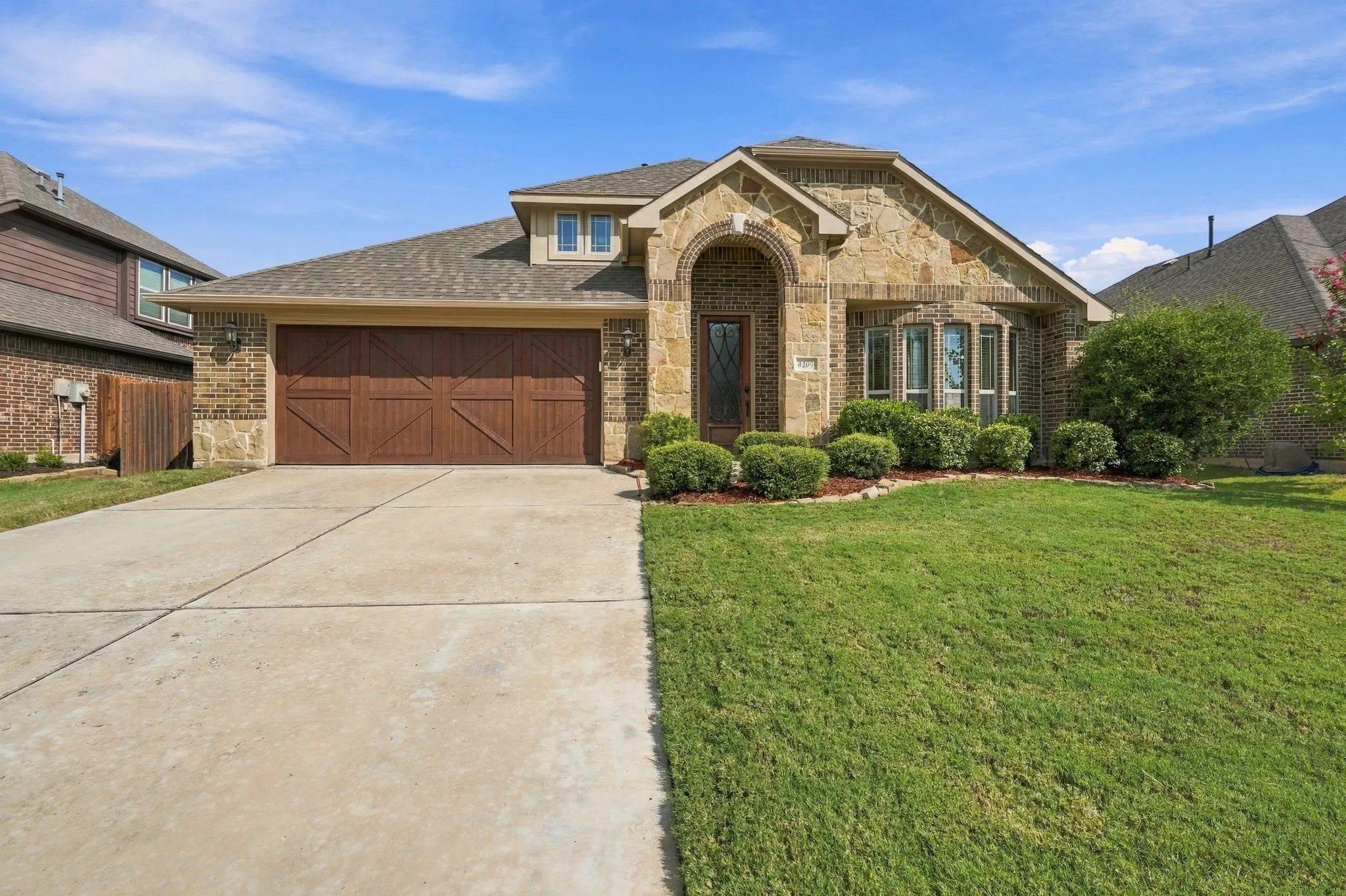 Gorgeous curb appeal with brick & stone exterior, arched entry, manicured lawn & landscaping