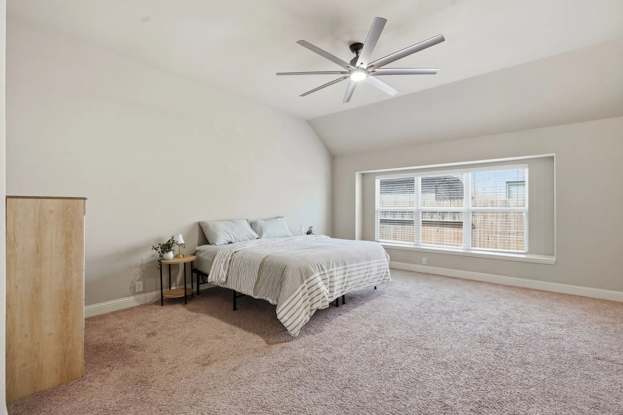 Vaulted ceiling with an attached ceiling fan, expansive window, and wall-to-wall carpeting