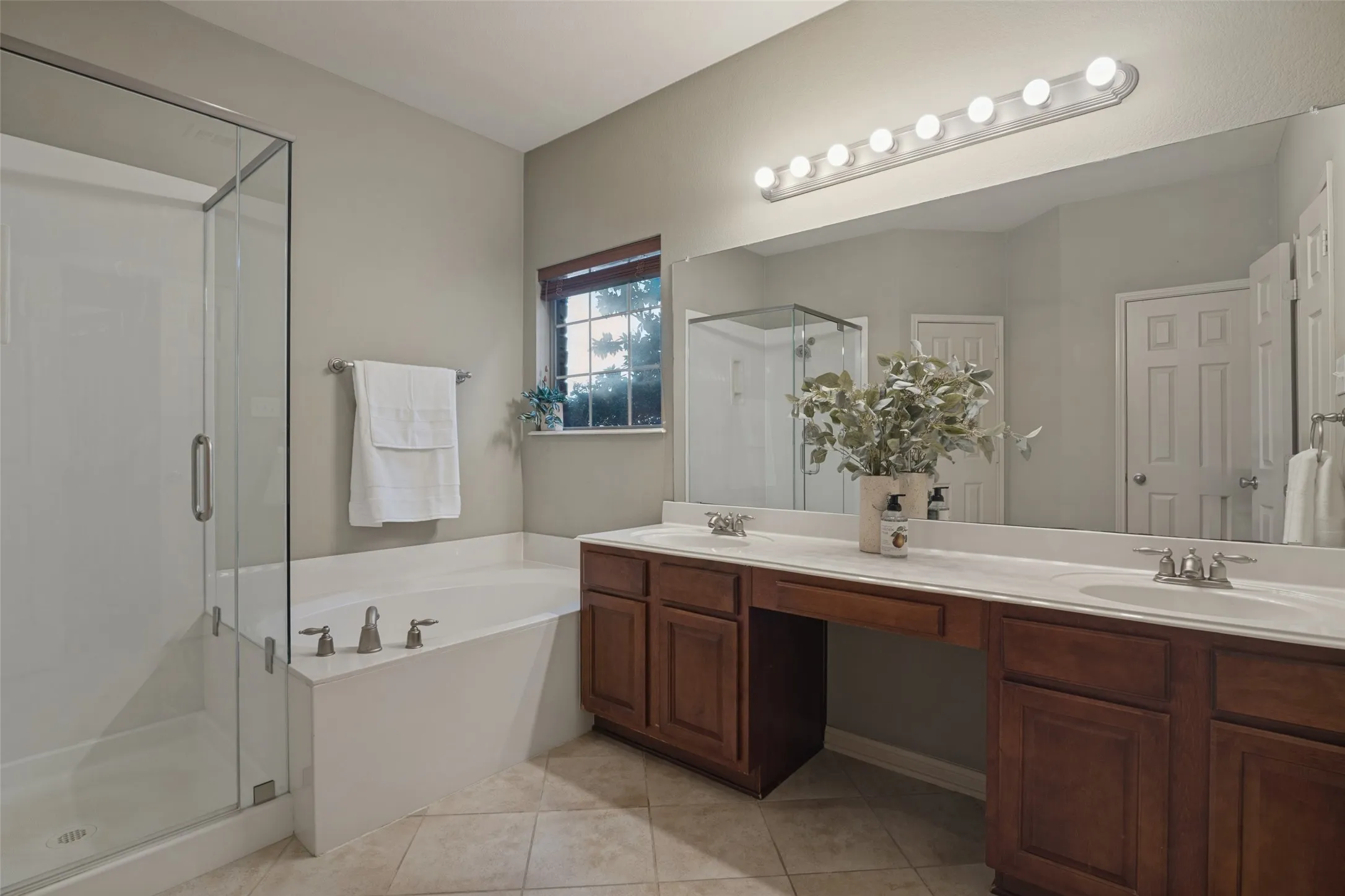 the primary ensuite bath features Glass-enclosed shower, built-in soaking tub, dual vanity with undermount sinks, wood-finish cabinetry, and a large wall-mounted mirror, toilet closet and linen closet