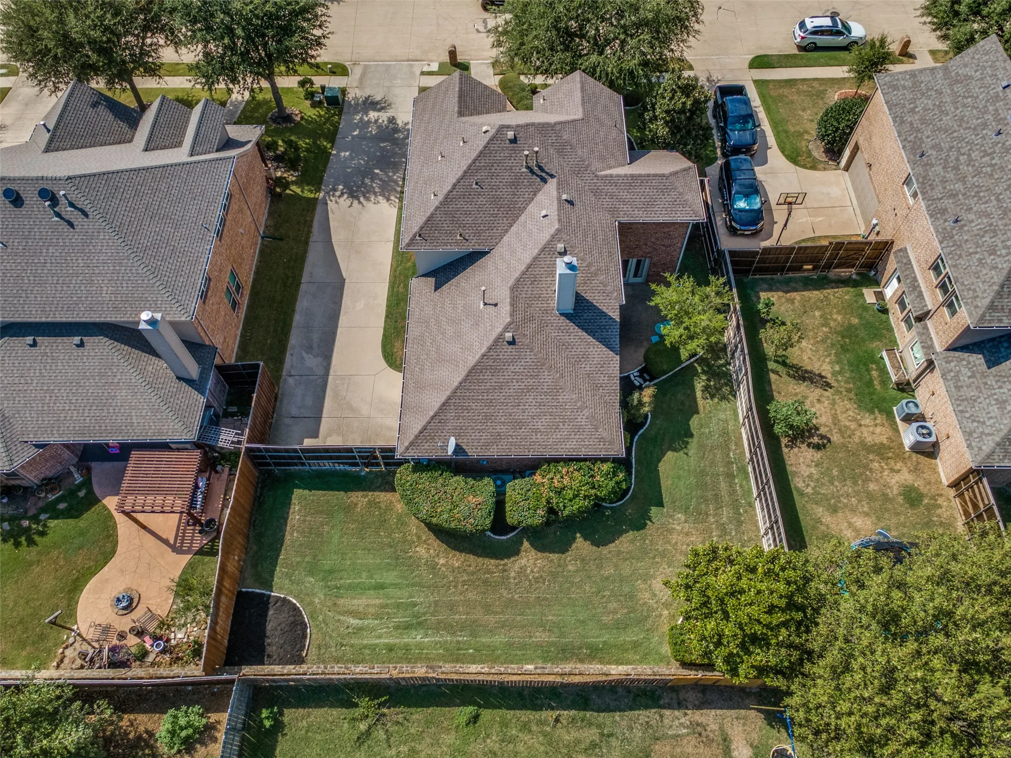 Expansive backyard featuring a manicured lawn, paved patio, and pergola