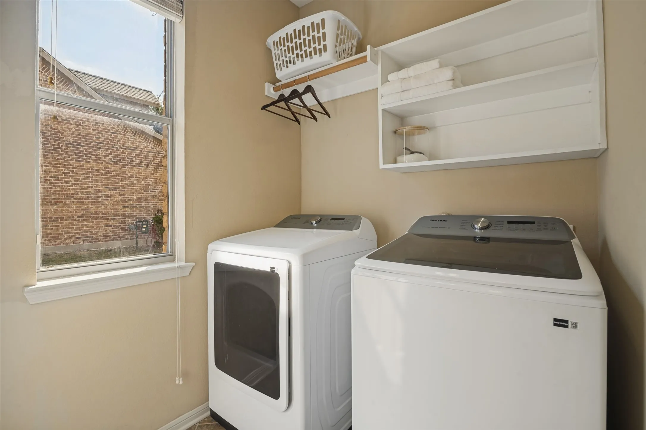 Brand New Washer and Dryer in the Laundry room with Window with white trim, built-in shelving, and a wall-mounted hanging rod