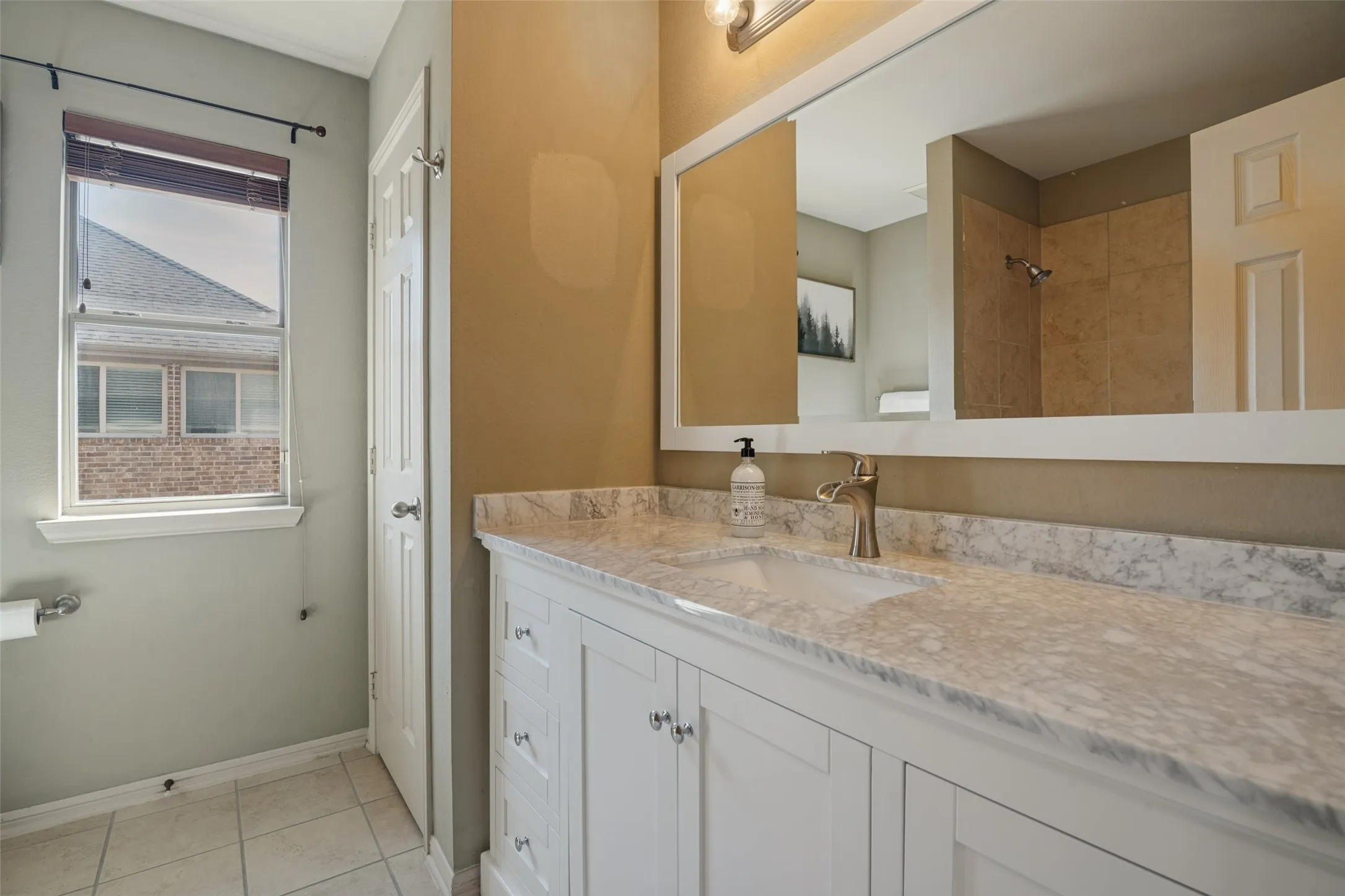 secondary bathroom #1 has White shaker vanity with a single basin sink, brushed nickel faucet, and a large framed mirror