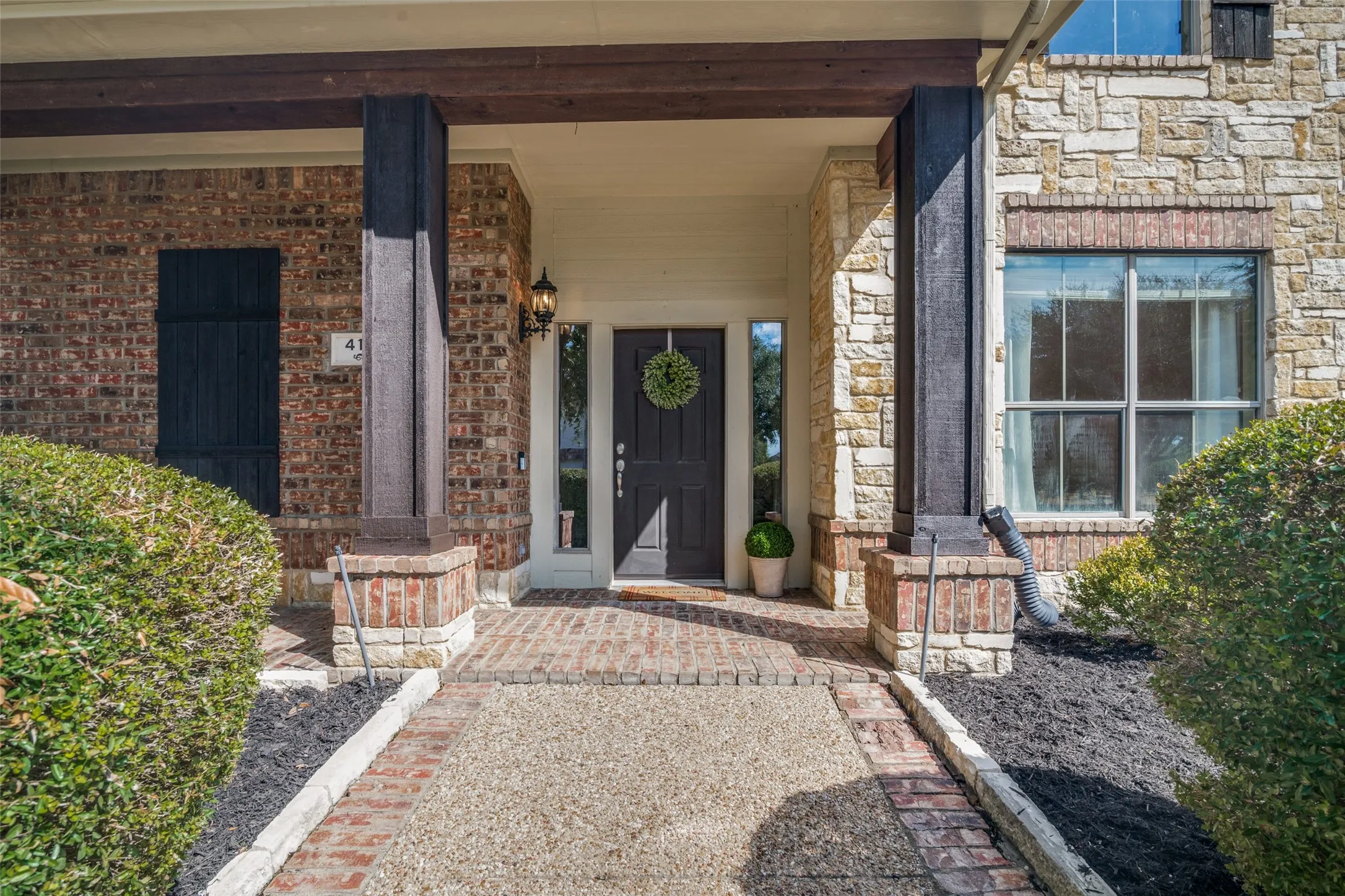Stone and brick exterior with dark wood-finish columns around your front door