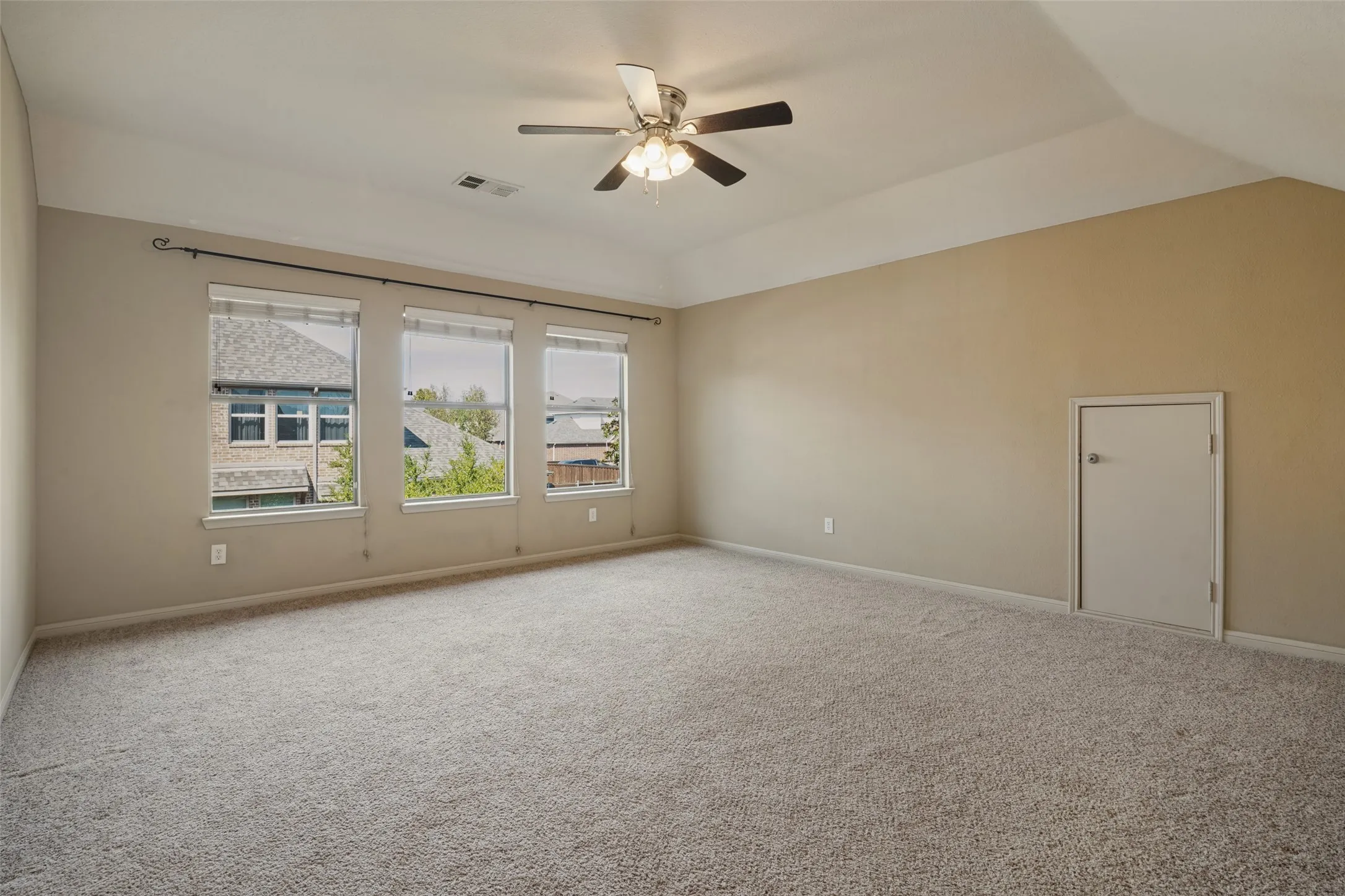 The large game room has potential for future second primary suite as there is a bathroom off of this room it has Vaulted ceiling with integrated ceiling fan, three windows with roller shades, and plush carpet flooring