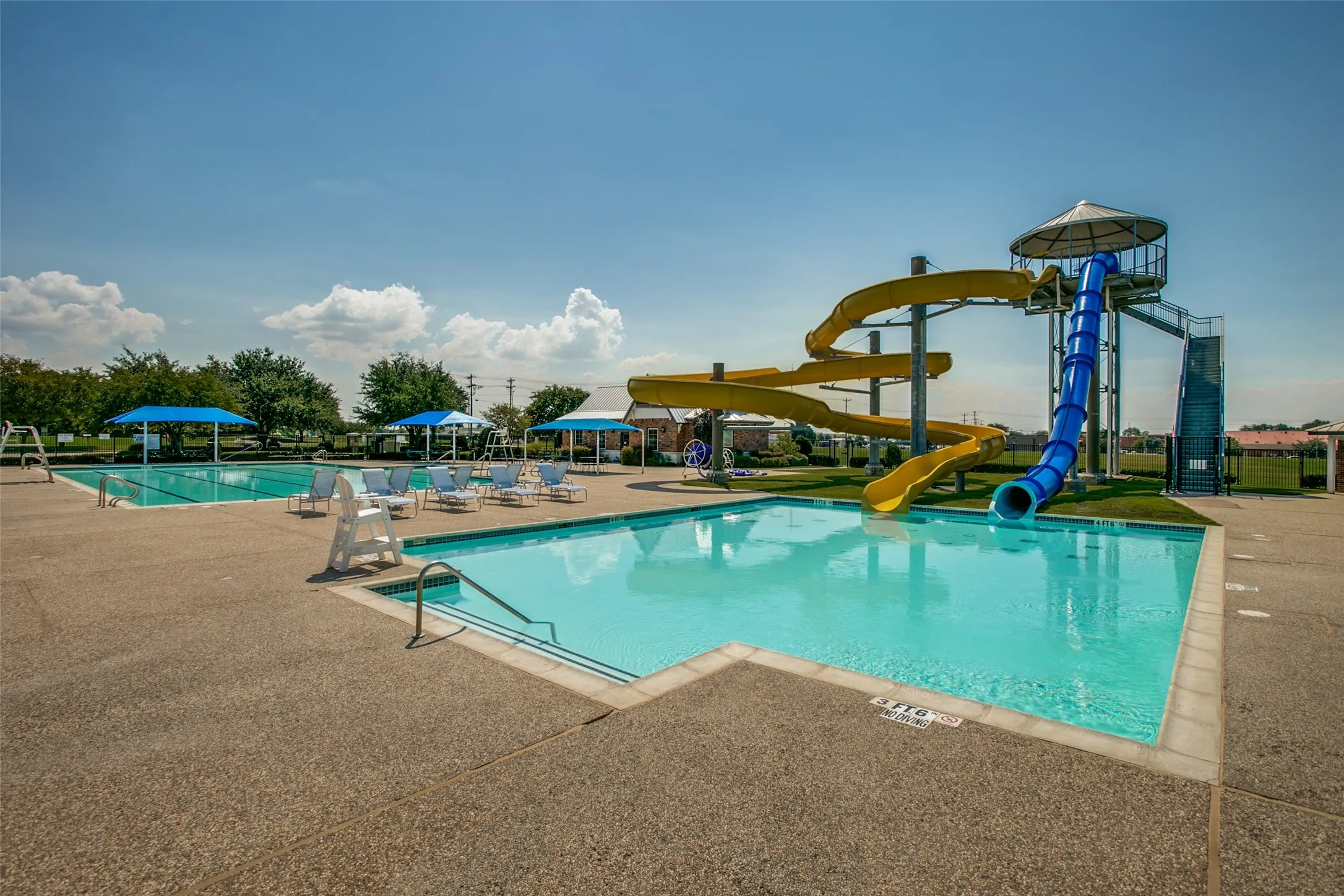 Swimming pool area featuring a large water slide structure, additional lap pool, and multiple shade structures