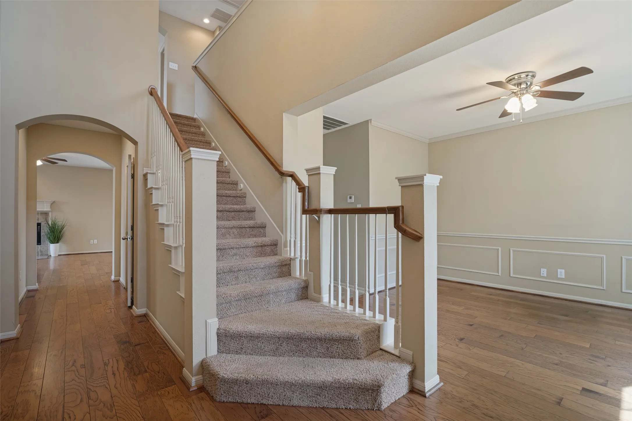 Soaring ceilings in the entryway Hardwood flooring, carpeted staircase with white balusters and wood-finish handrail, decorative wall molding, and recessed lighting