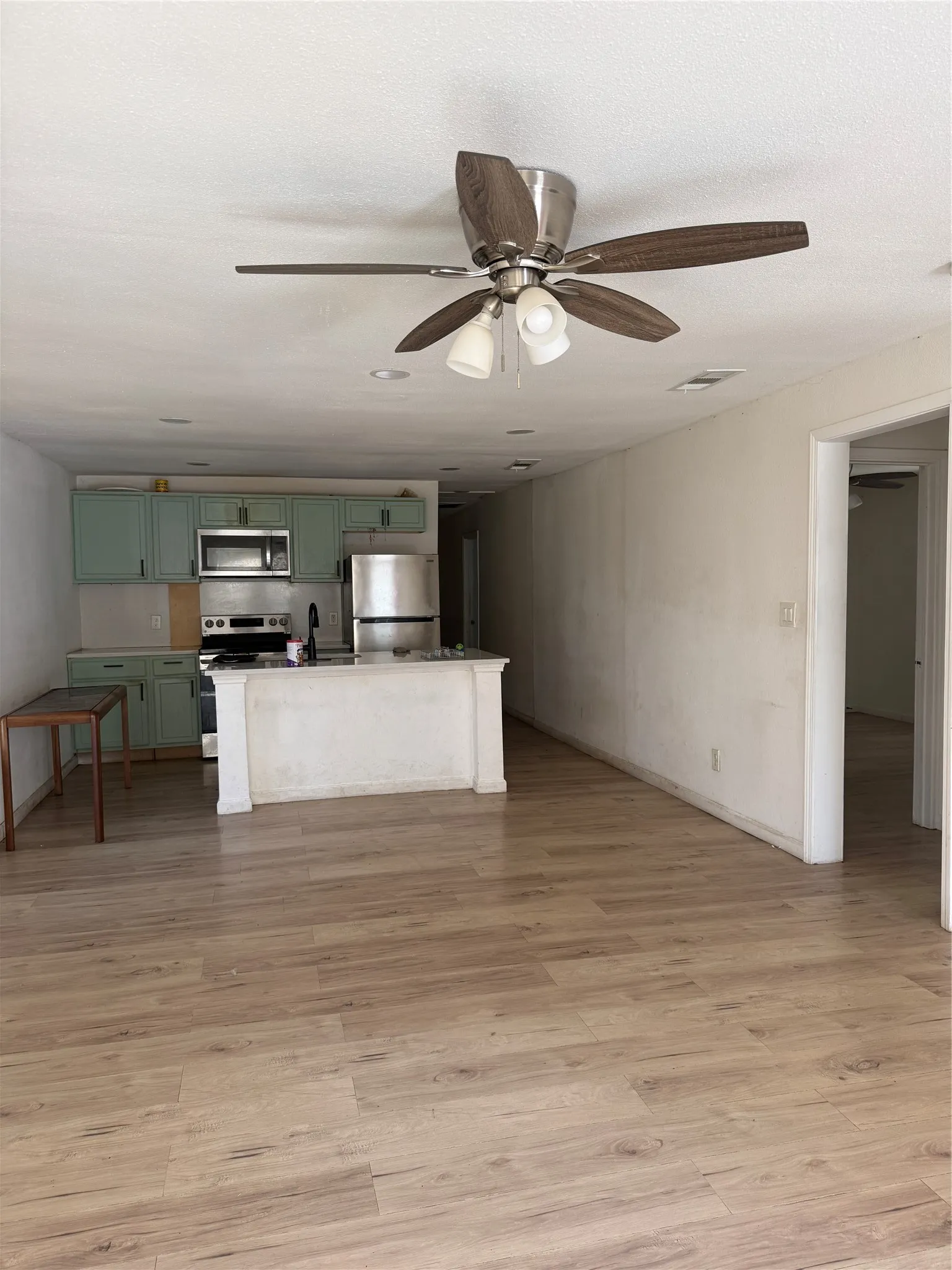 Open-concept living area featuring wood-finish flooring, a ceiling fan with integrated lighting, and recessed lighting