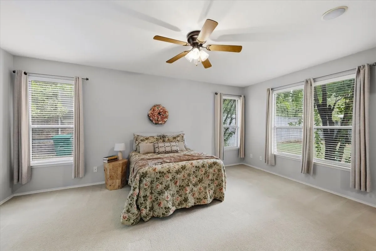 Recessed lighting, wood-finish ceiling fan, multiple windows with blinds, and light-toned carpeting