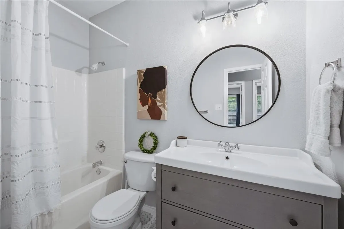 Bathroom featuring a white bathtub, white subway tile surround, white toilet, and a vanity with an integrated sink