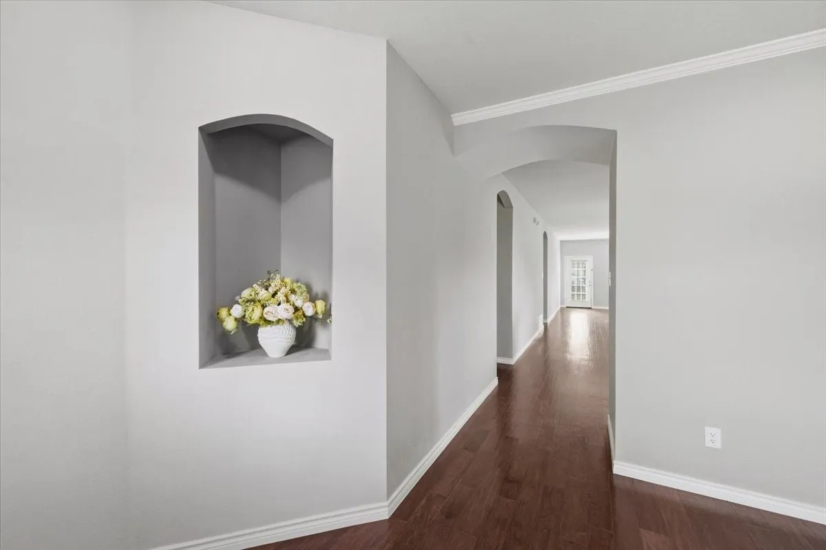 Arched wall niche, crown molding, archway, wood-finish flooring, and white trim