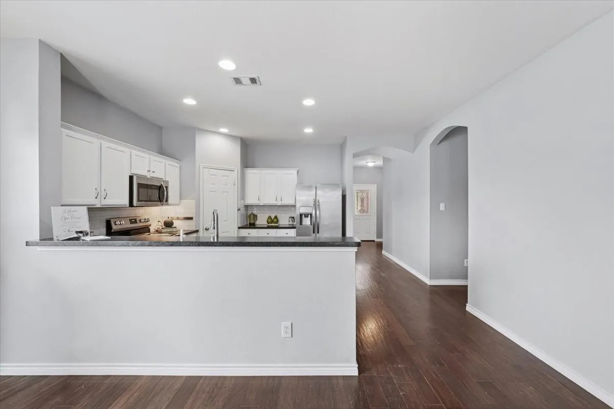 Kitchen with white cabinetry, dark countertops, and stainless steel appliances