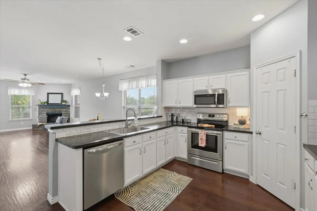 Kitchen featuring white cabinetry, dark countertops, stainless steel appliances, and a tile backsplash