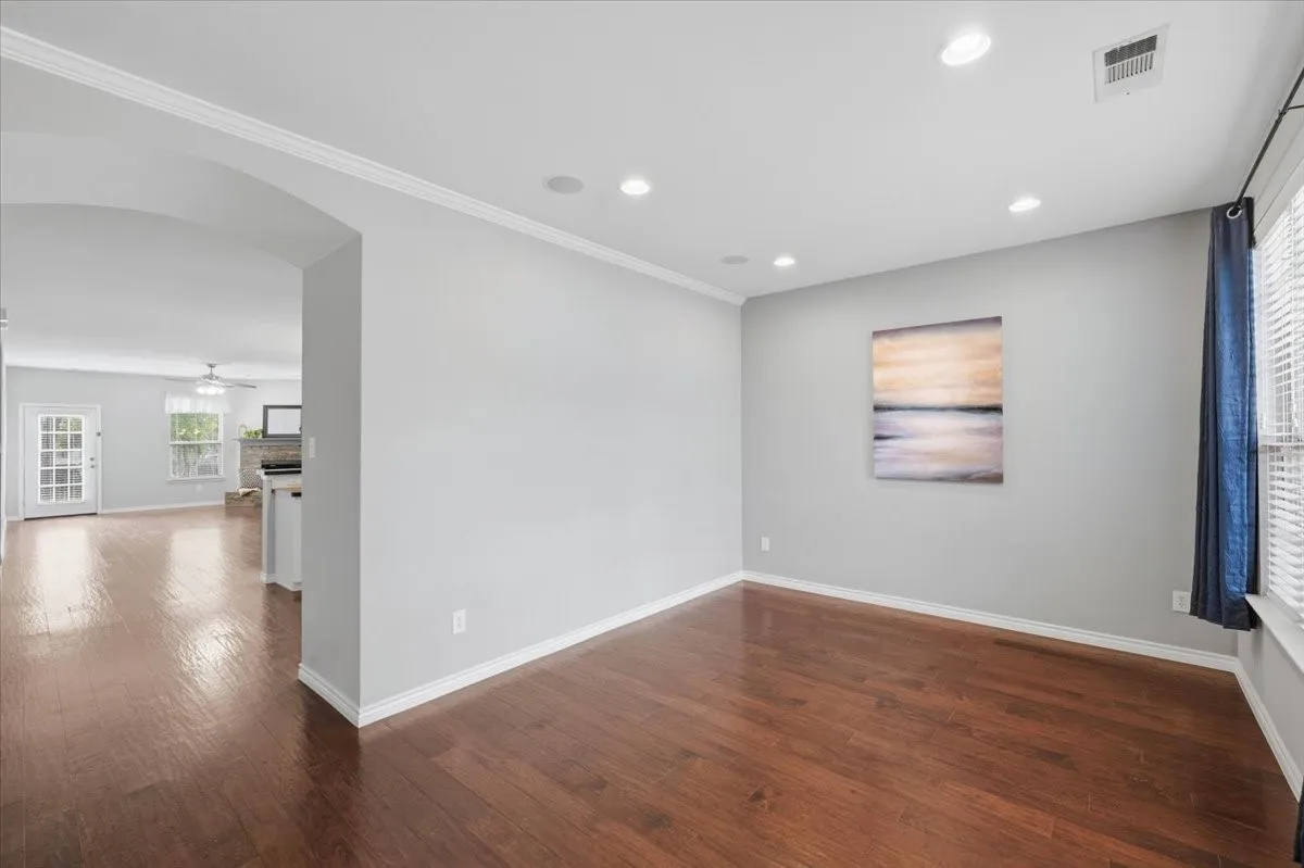 Wood-finish flooring throughout, recessed ceiling lighting, crown molding, and an arched doorway