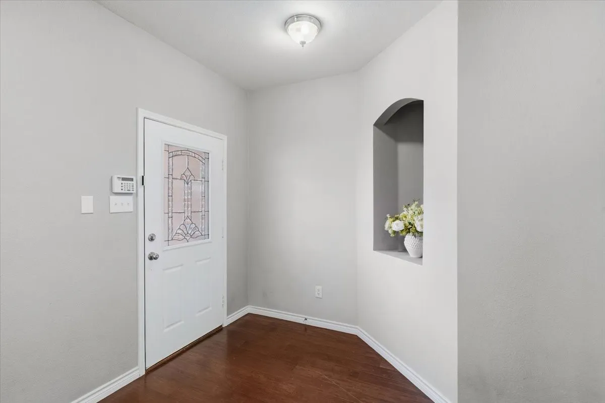 Entryway featuring wood-finish flooring, a white door with decorative glass, and a built-in arched alcove
