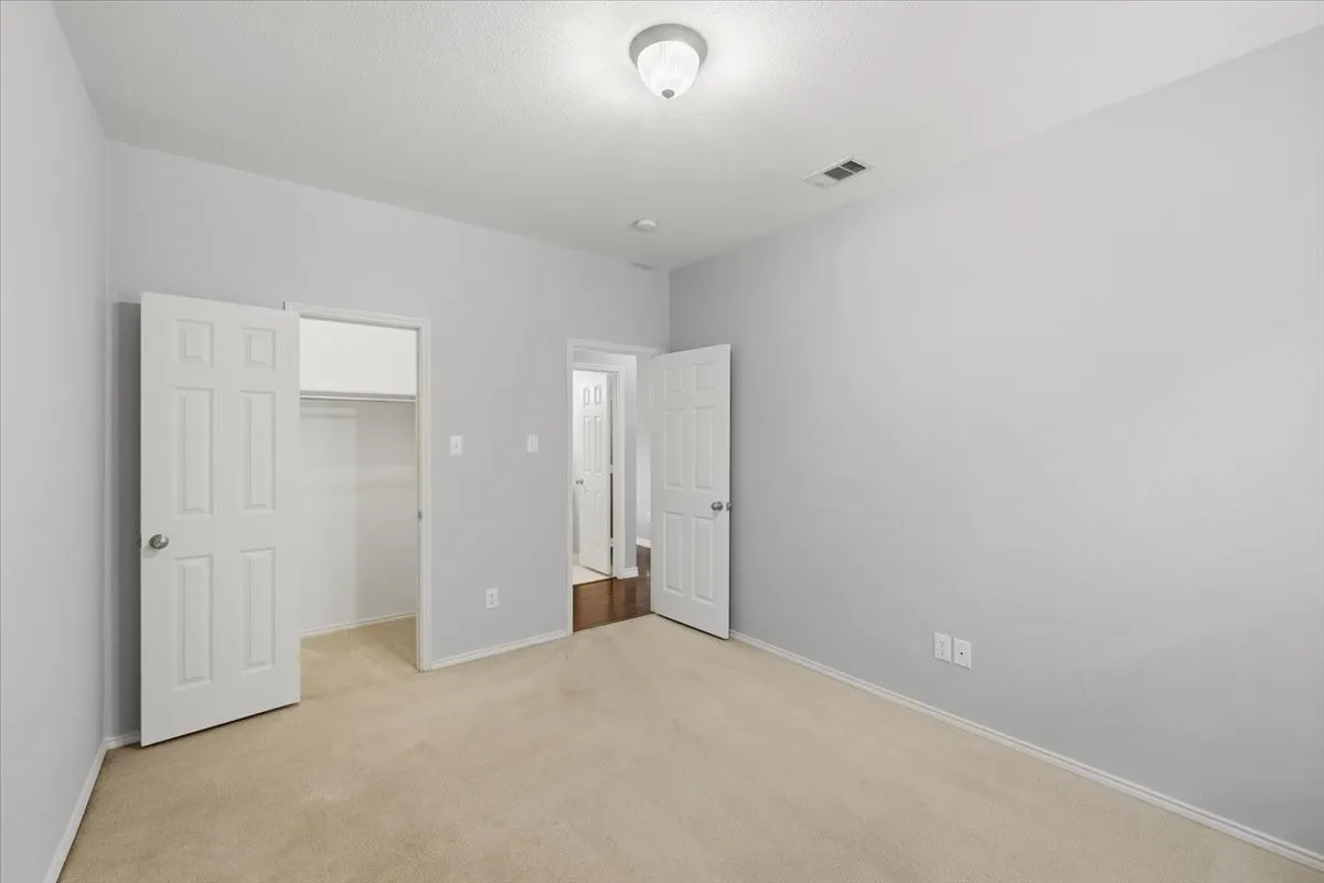 Light-colored walls, carpeted flooring, and a flush mount ceiling light fixture