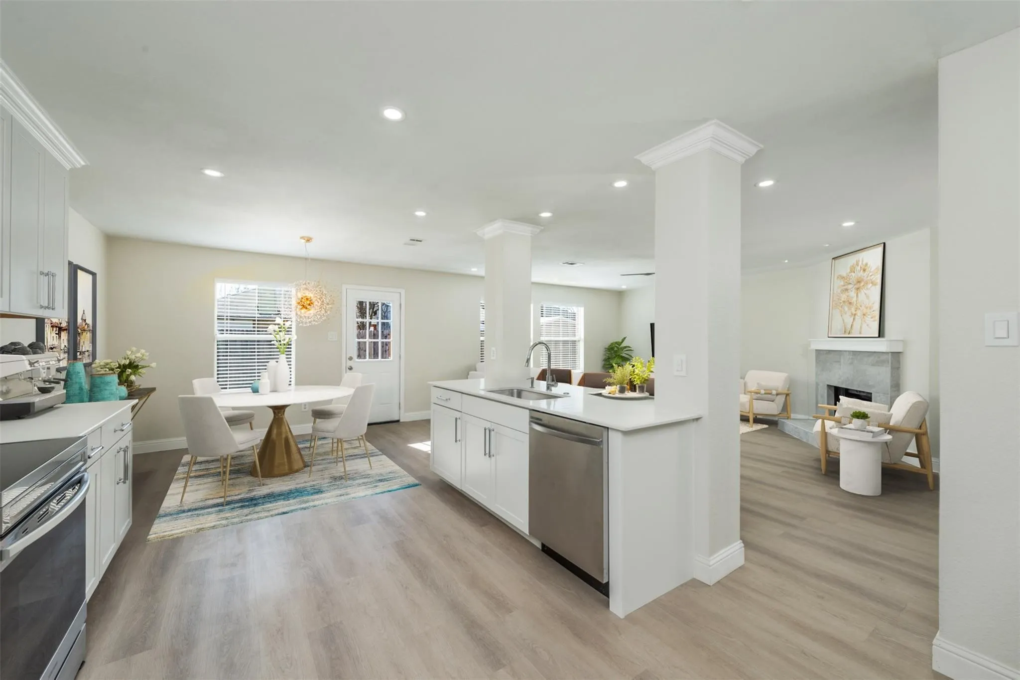 Kitchen featuring stove, light wood-type flooring, sink, stainless steel dishwasher, and a tiled fireplace