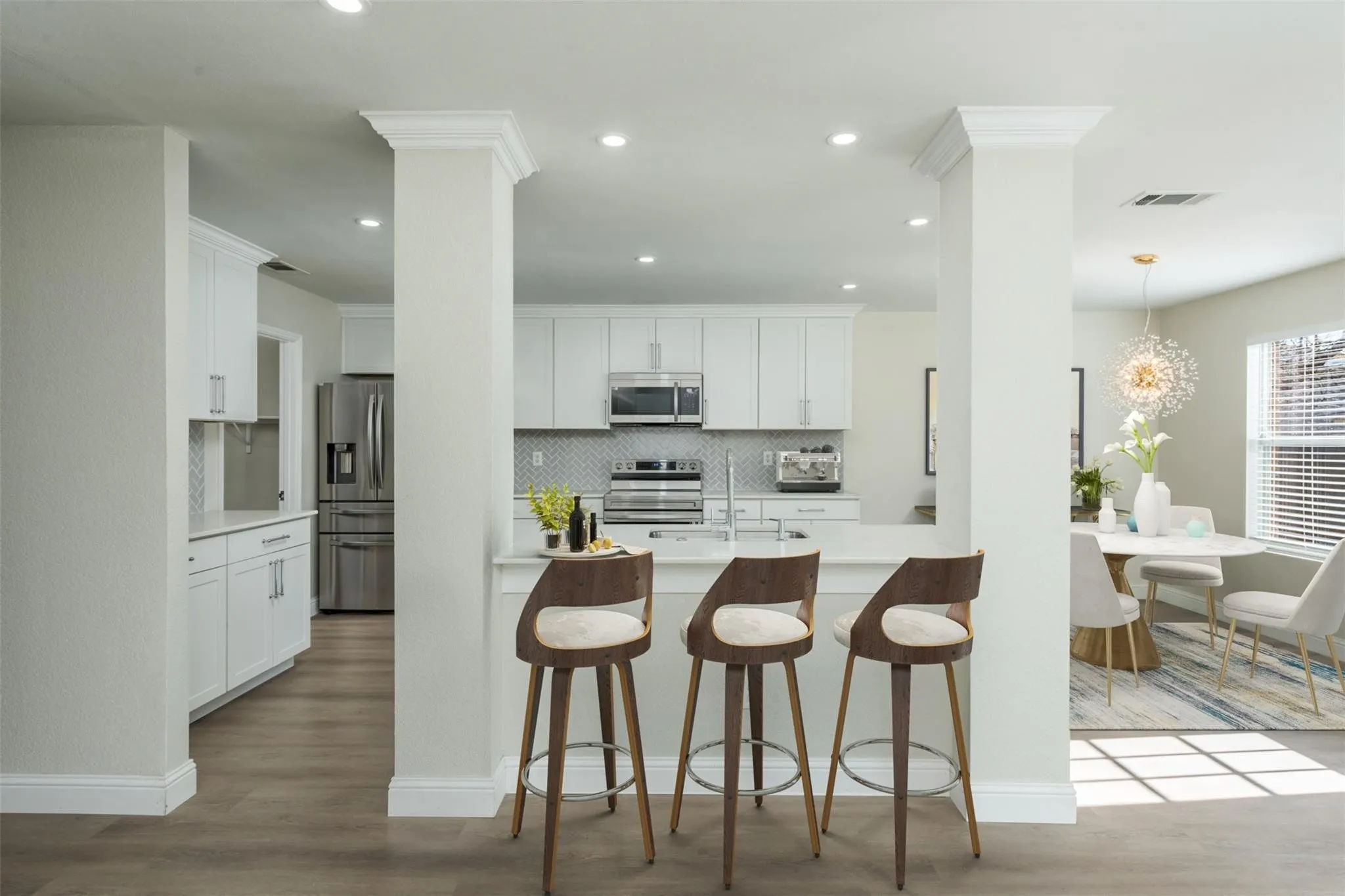 Kitchen featuring light hardwood / wood-style flooring, appliances with stainless steel finishes, white cabinetry, and backsplash