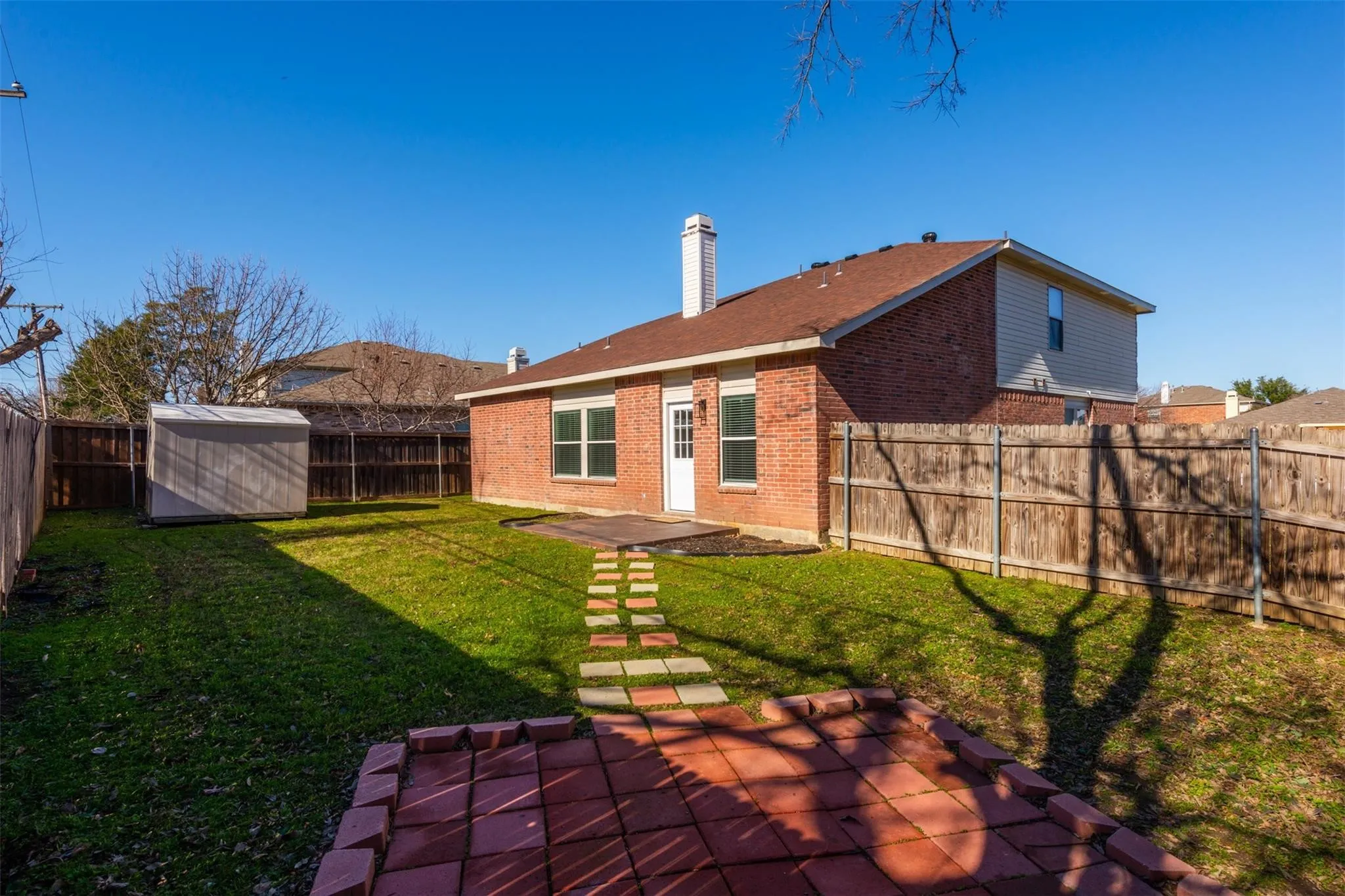 Rear view of house with a lawn, a patio, and a shed