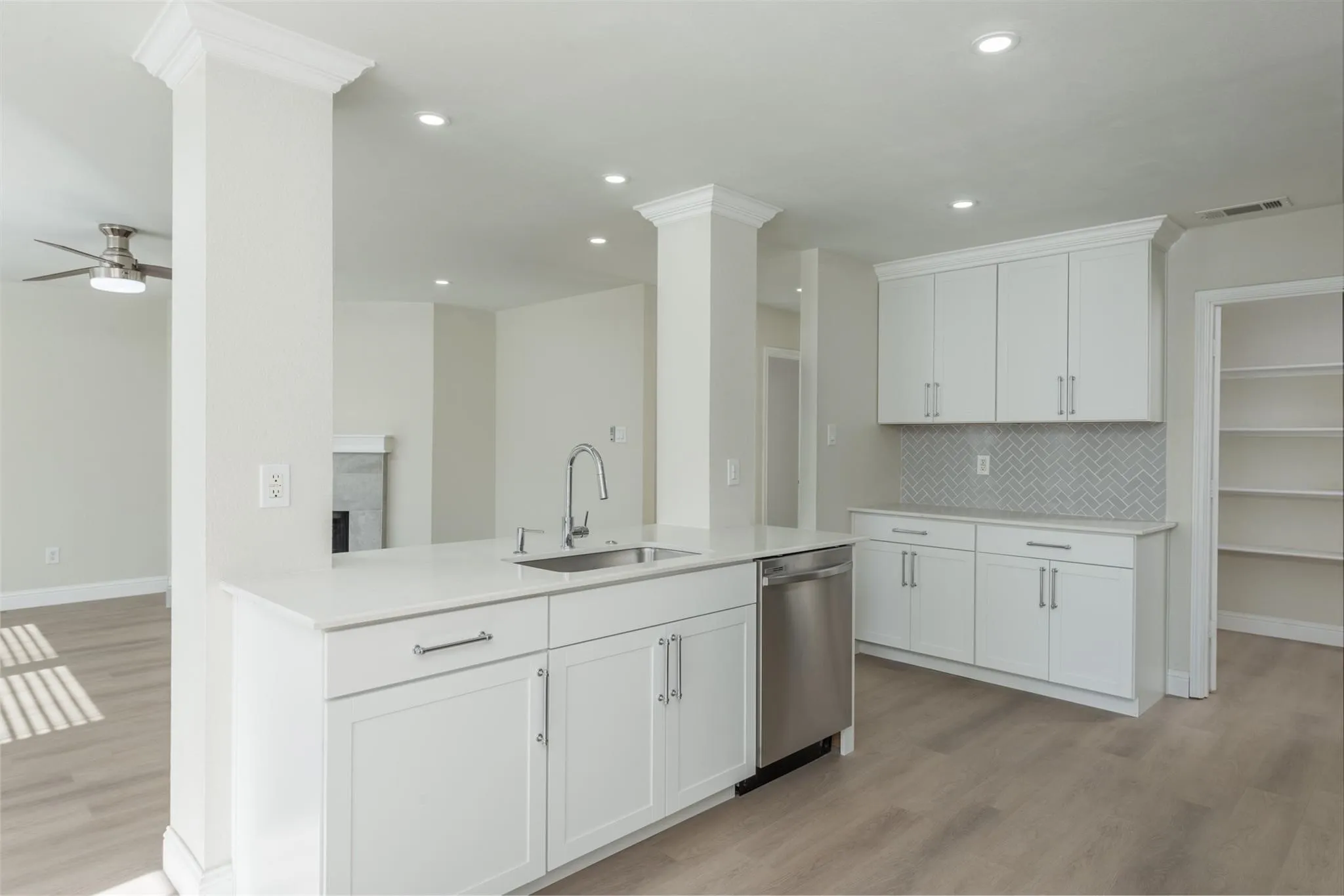 Kitchen featuring light wood-type flooring, ceiling fan, sink, tasteful backsplash, and stainless steel dishwasher
