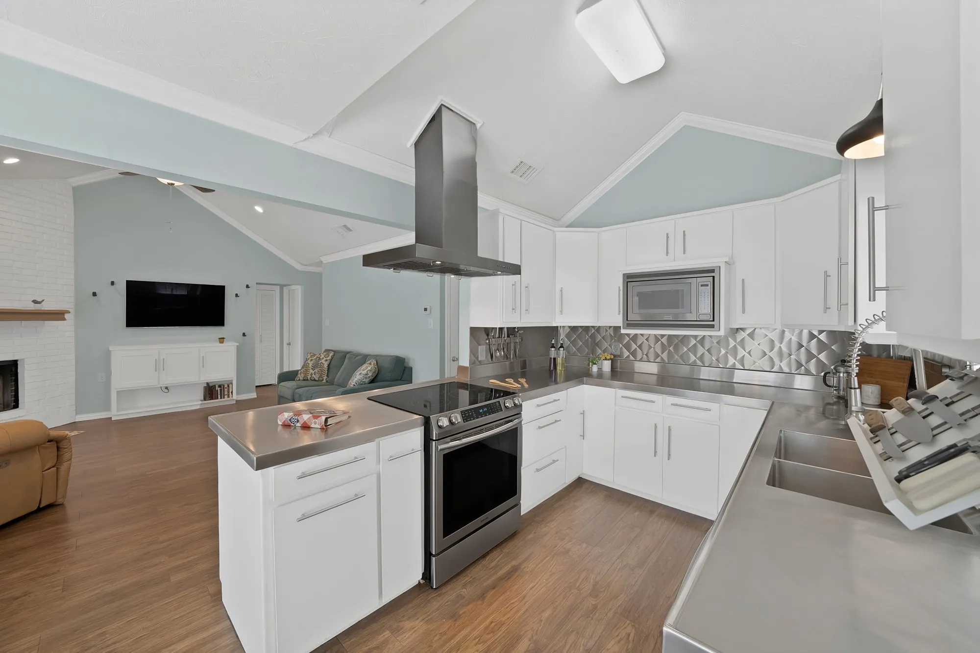 Kitchen featuring stainless steel countertops, built-in microwave, and a range with overhead exhaust hood