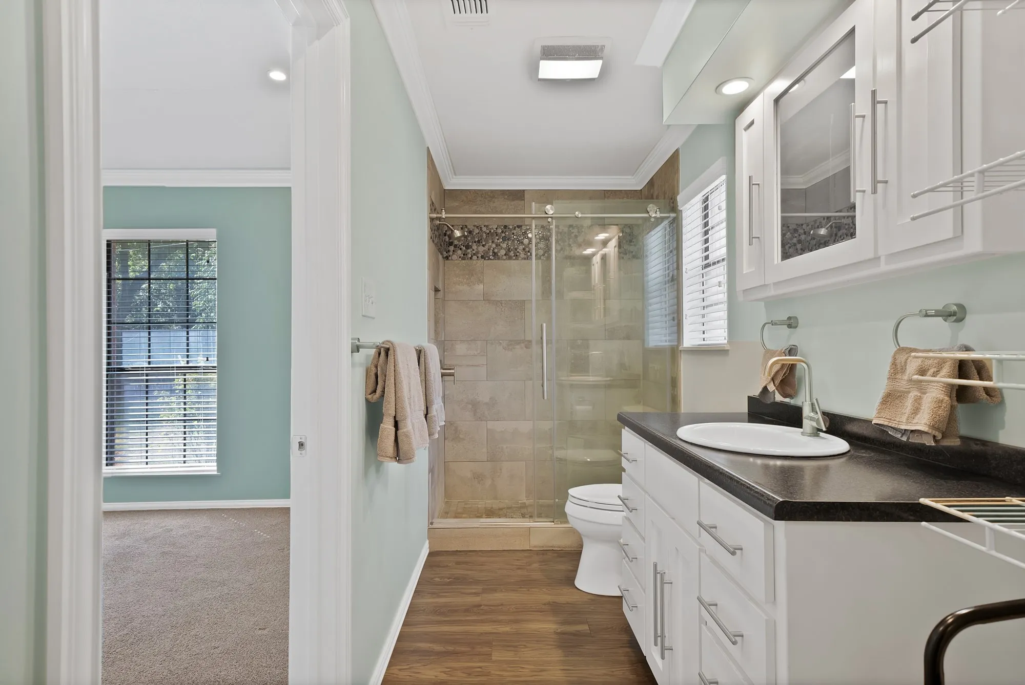 Bathroom featuring a single vanity with a dark countertop, white cabinetry, and an undermount sink