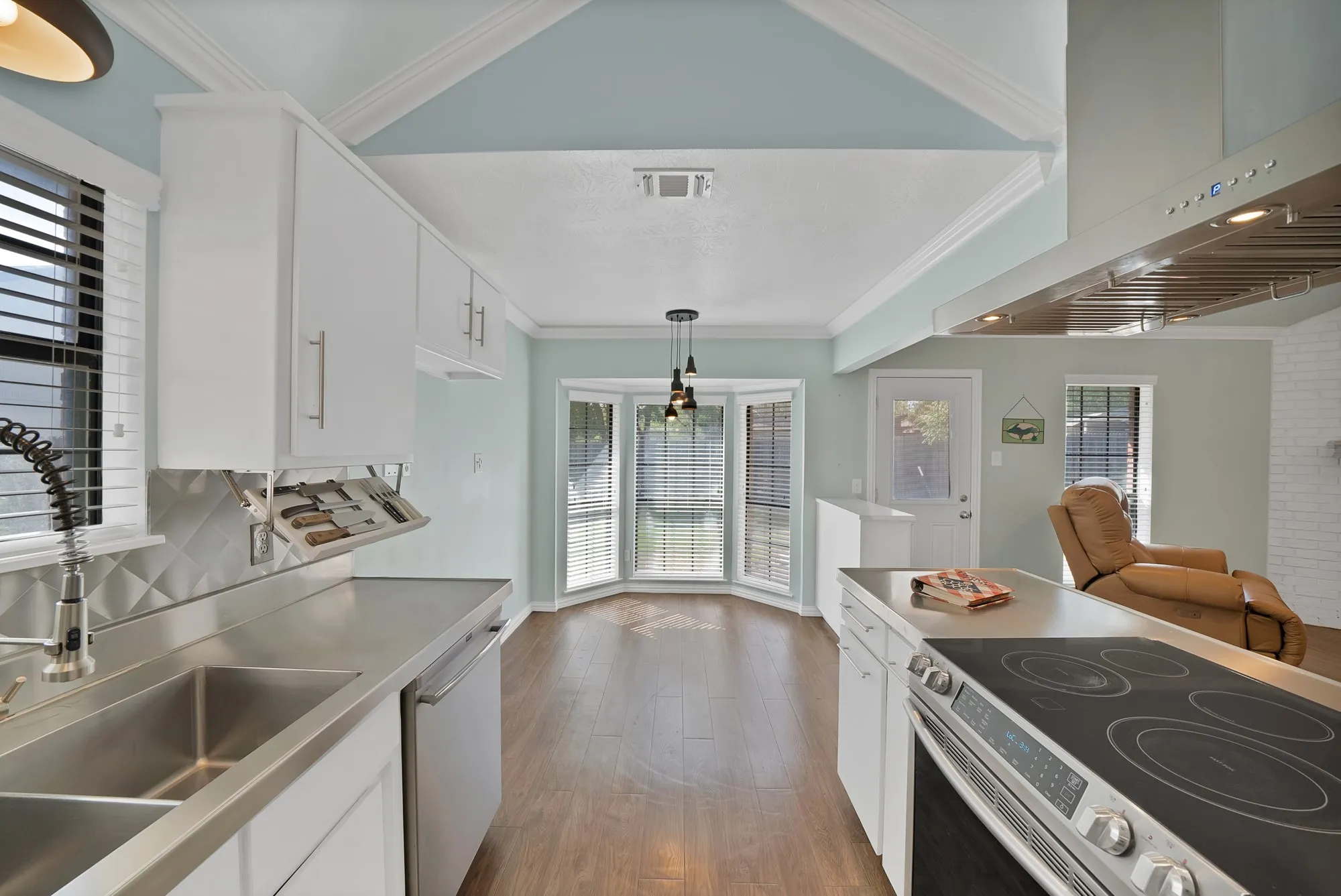 Kitchen featuring white cabinetry, stainless steel countertops, a built-in cooktop, and wood-finish flooring
