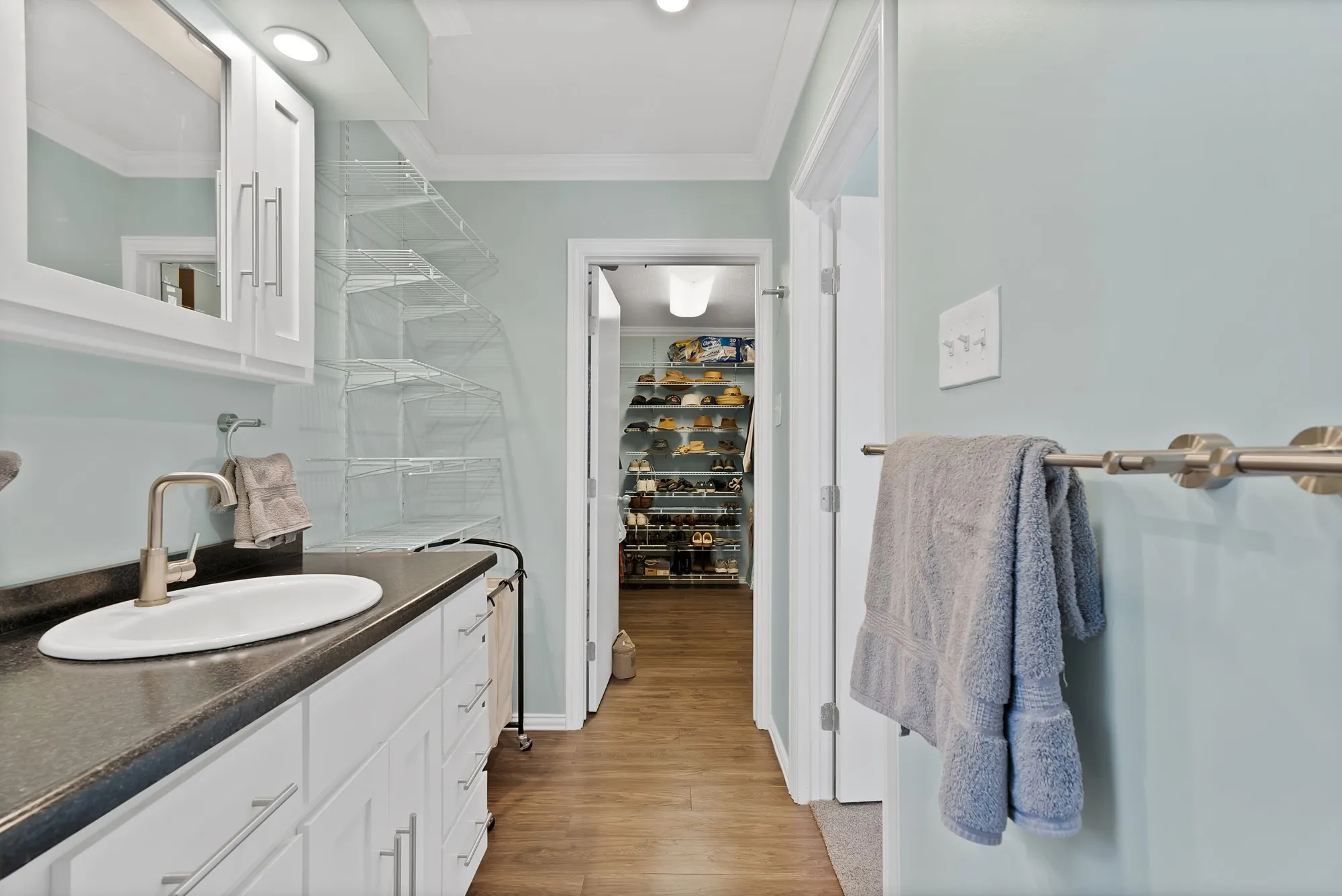 Vanity with white cabinetry, a dark countertop, and an undermount sink