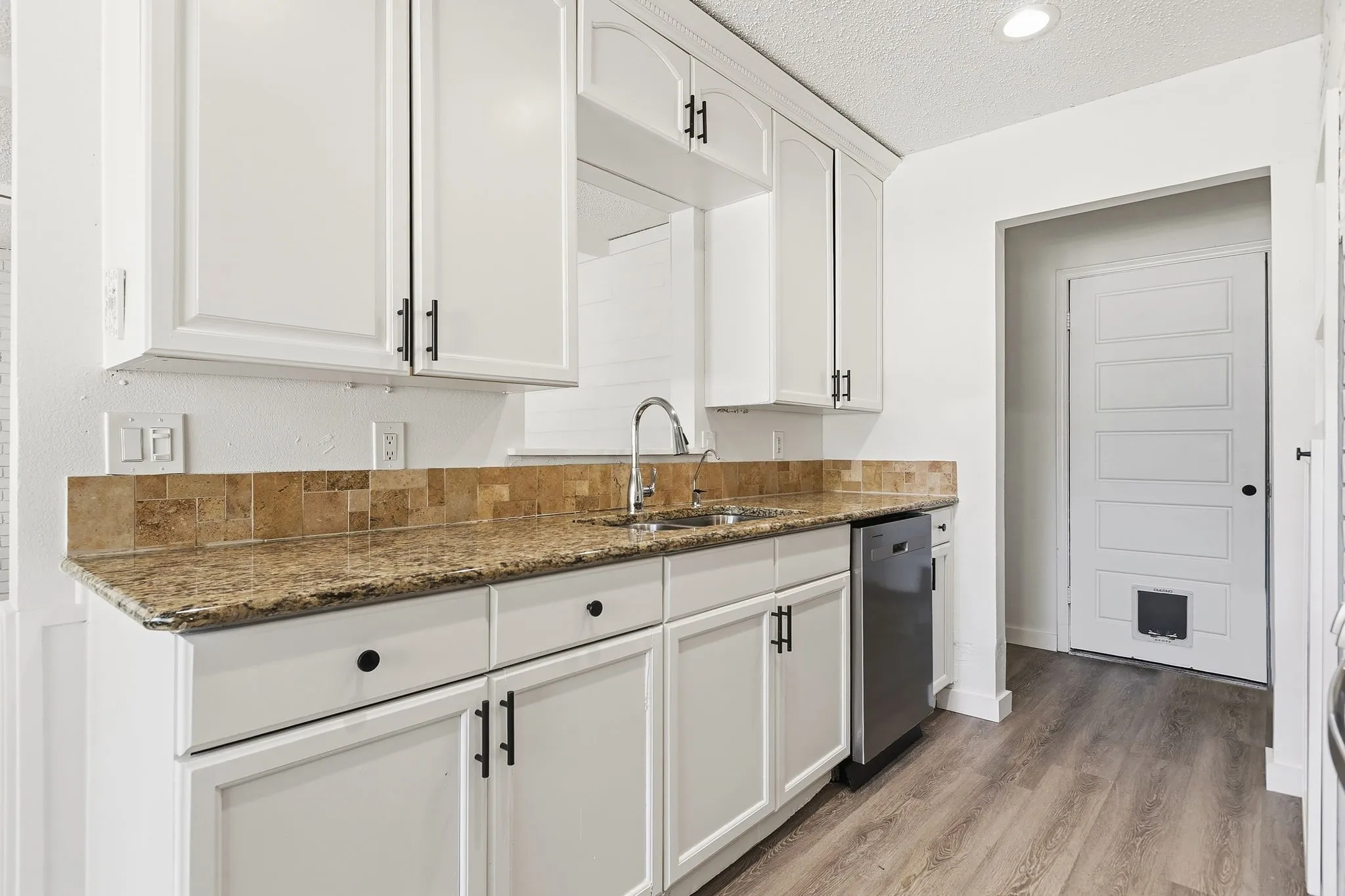 White shaker cabinetry with dark hardware and a tiled backsplash