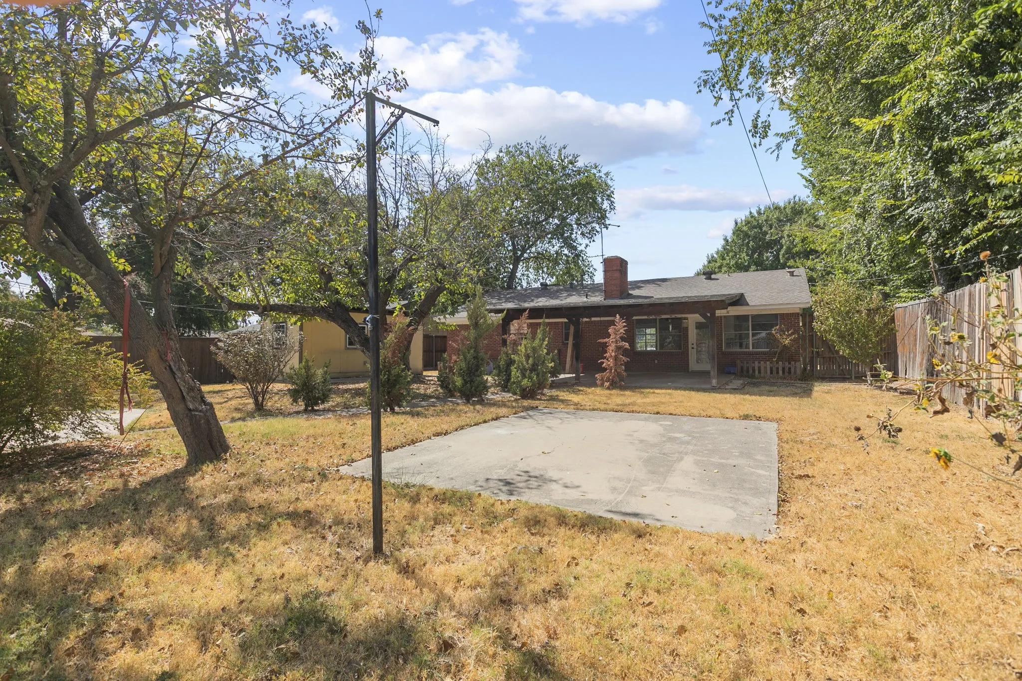 Backyard featuring a concrete patio, mature trees, and a privacy fence