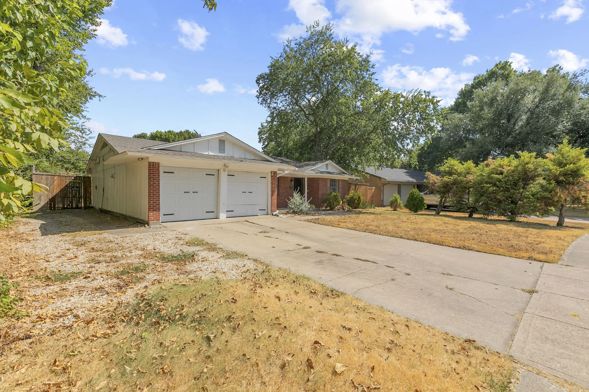 Exterior featuring a two-car garage, brick accents, and a paved driveway