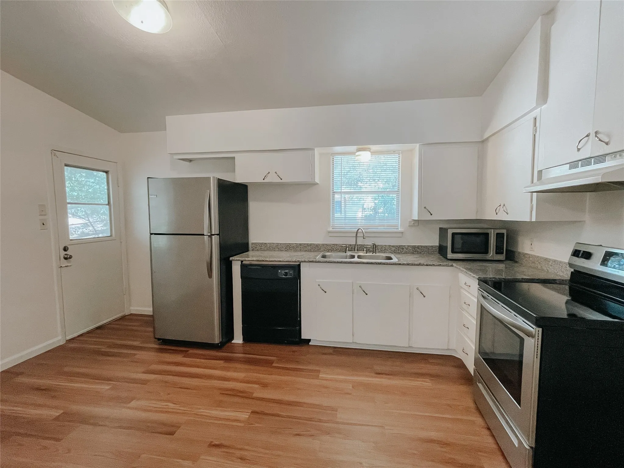 Kitchen with white cabinets, light hardwood / wood-style flooring, stainless steel appliances, and sink