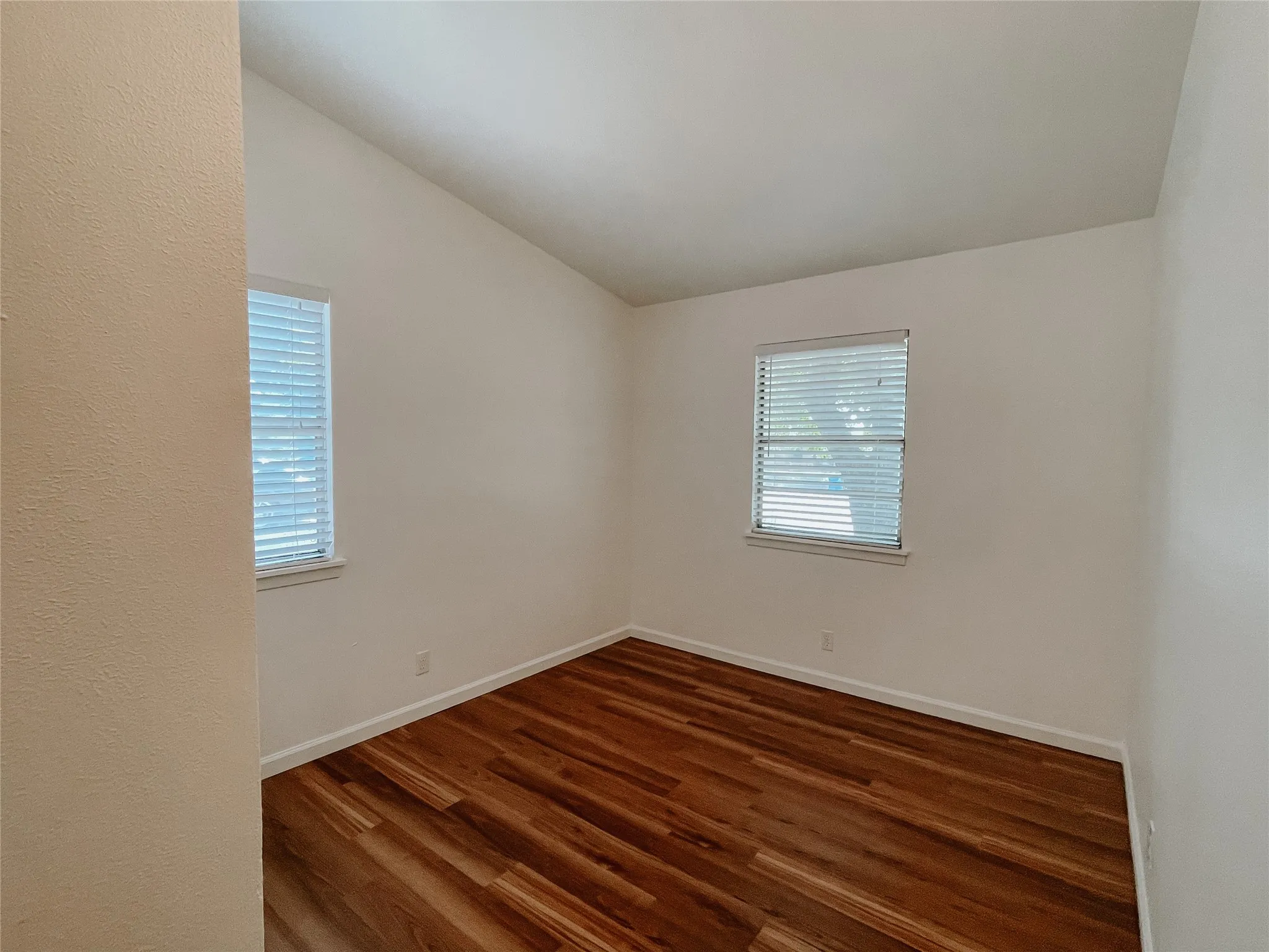 Unfurnished room with lofted ceiling and dark hardwood / wood-style floors