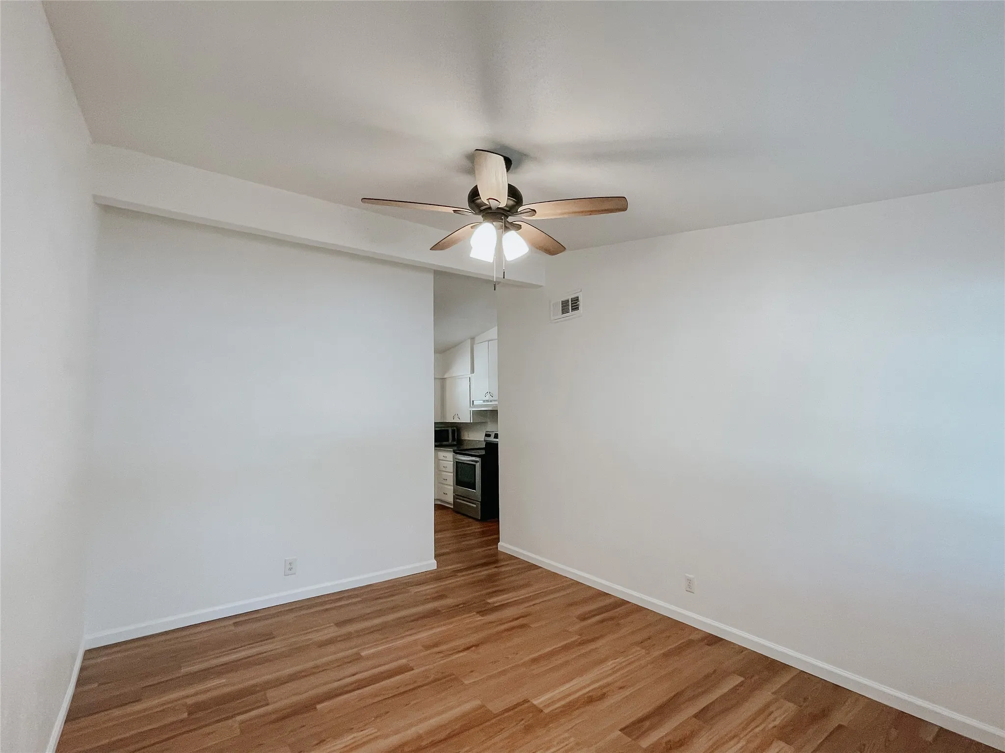 Spare room with light wood-type flooring, vaulted ceiling, and ceiling fan