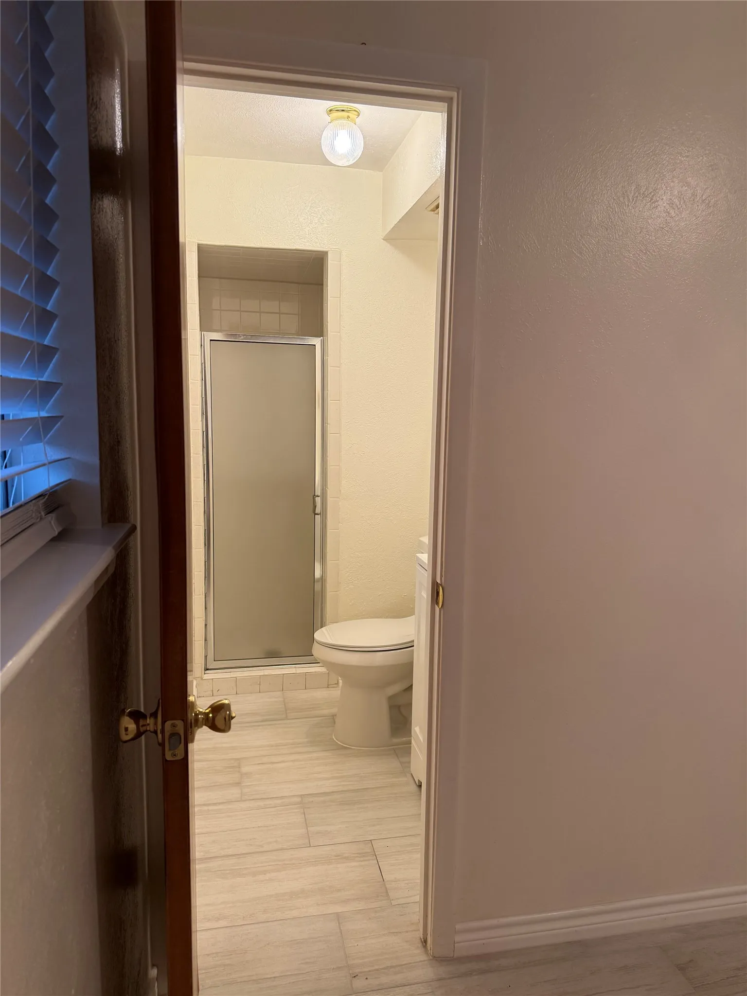 Full bath with a shower stall and light wood-style floors