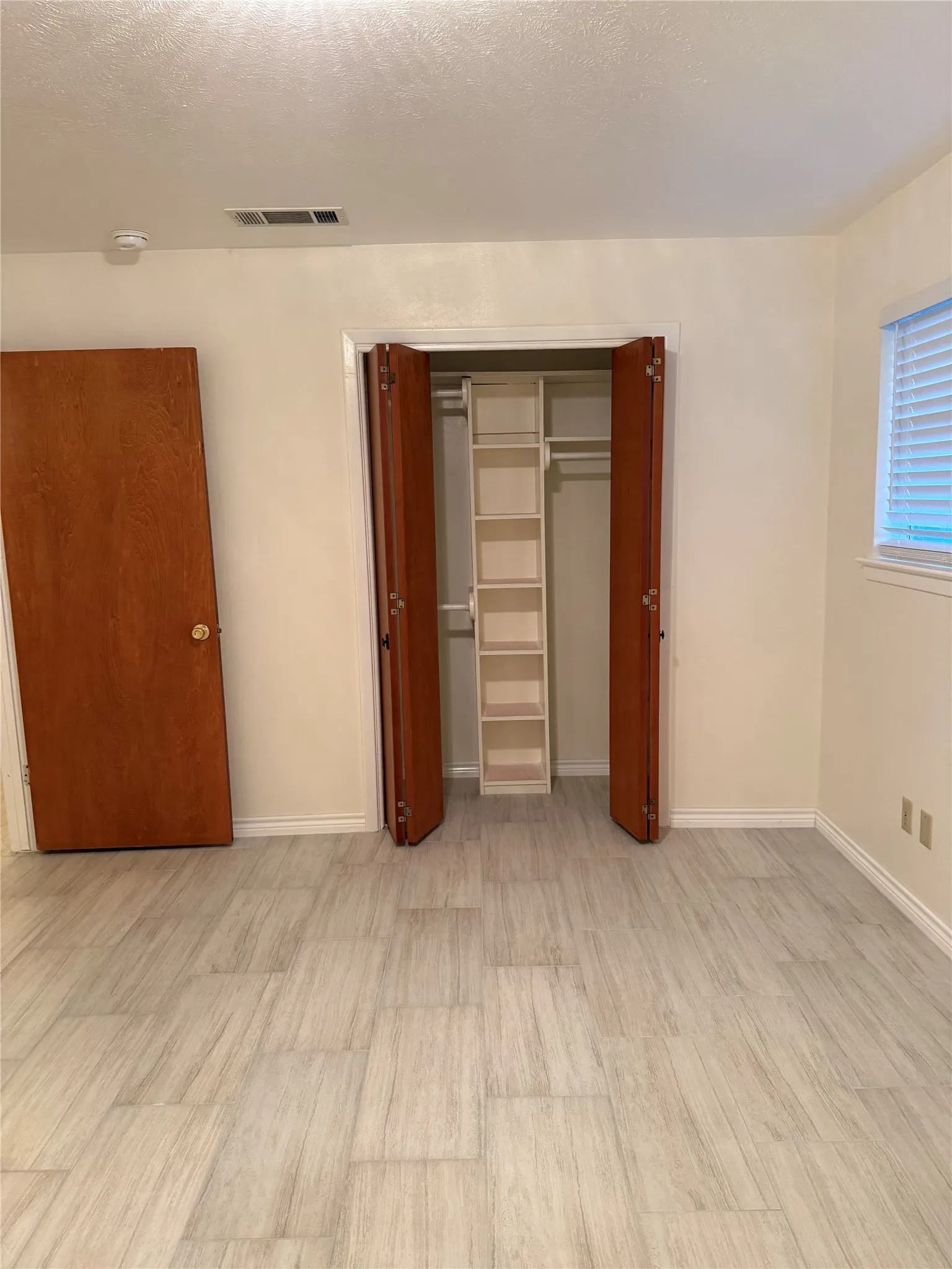 Unfurnished bedroom with a closet, light wood-style flooring, and a textured ceiling