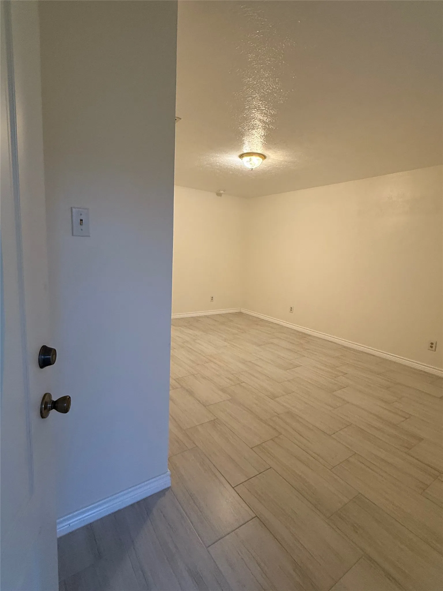 Empty room with a textured ceiling and light wood-style floors
