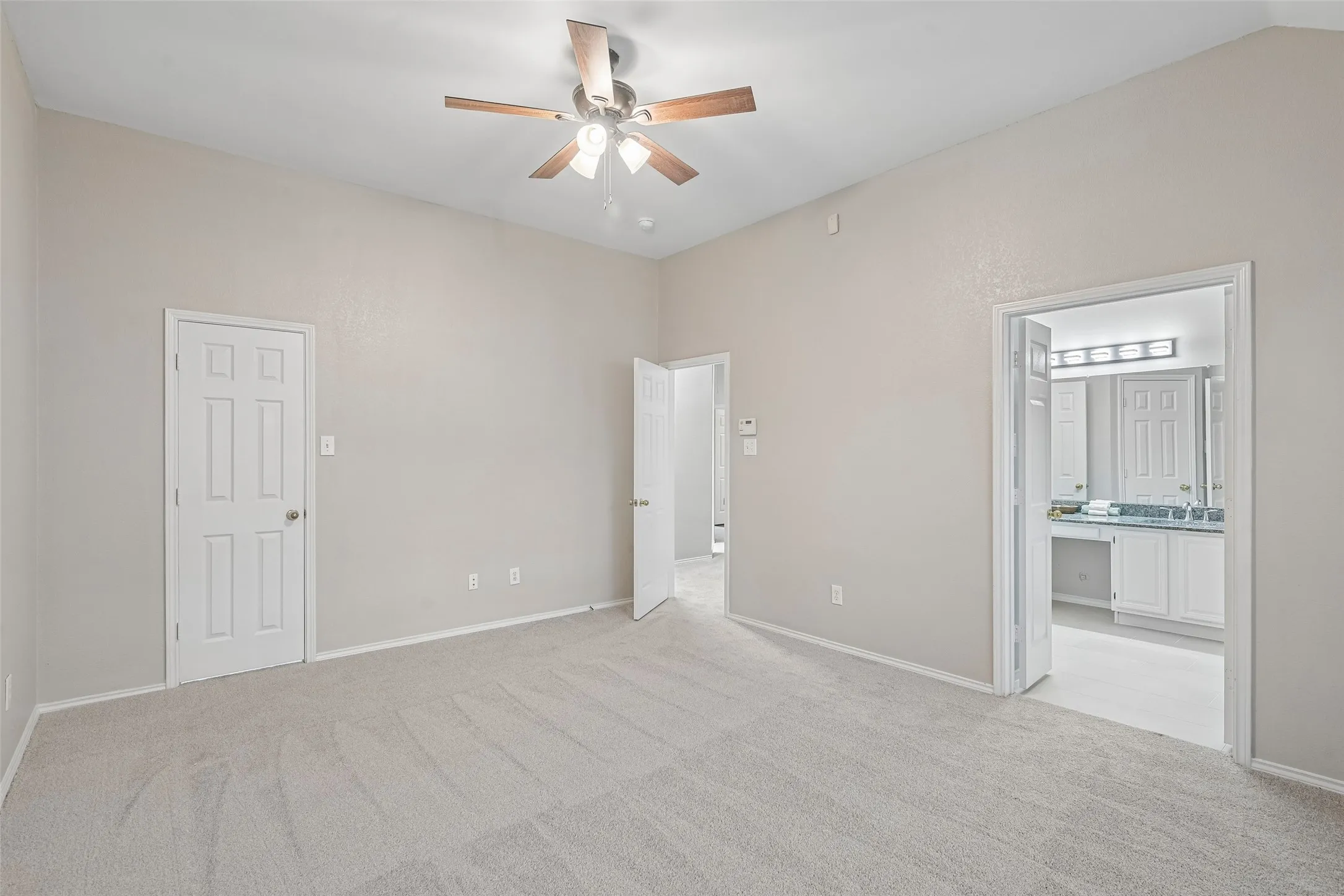 New Carpeted flooring, vaulted ceiling, ceiling fan with light fixture, white paneled doors, and an open doorway to an adjacent room