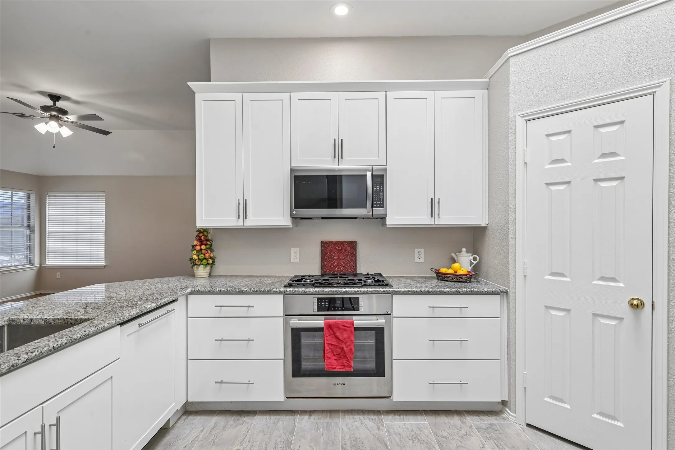 White shaker cabinetry, stainless steel appliances, built-in microwave, gas cooktop, and wood-finish flooring