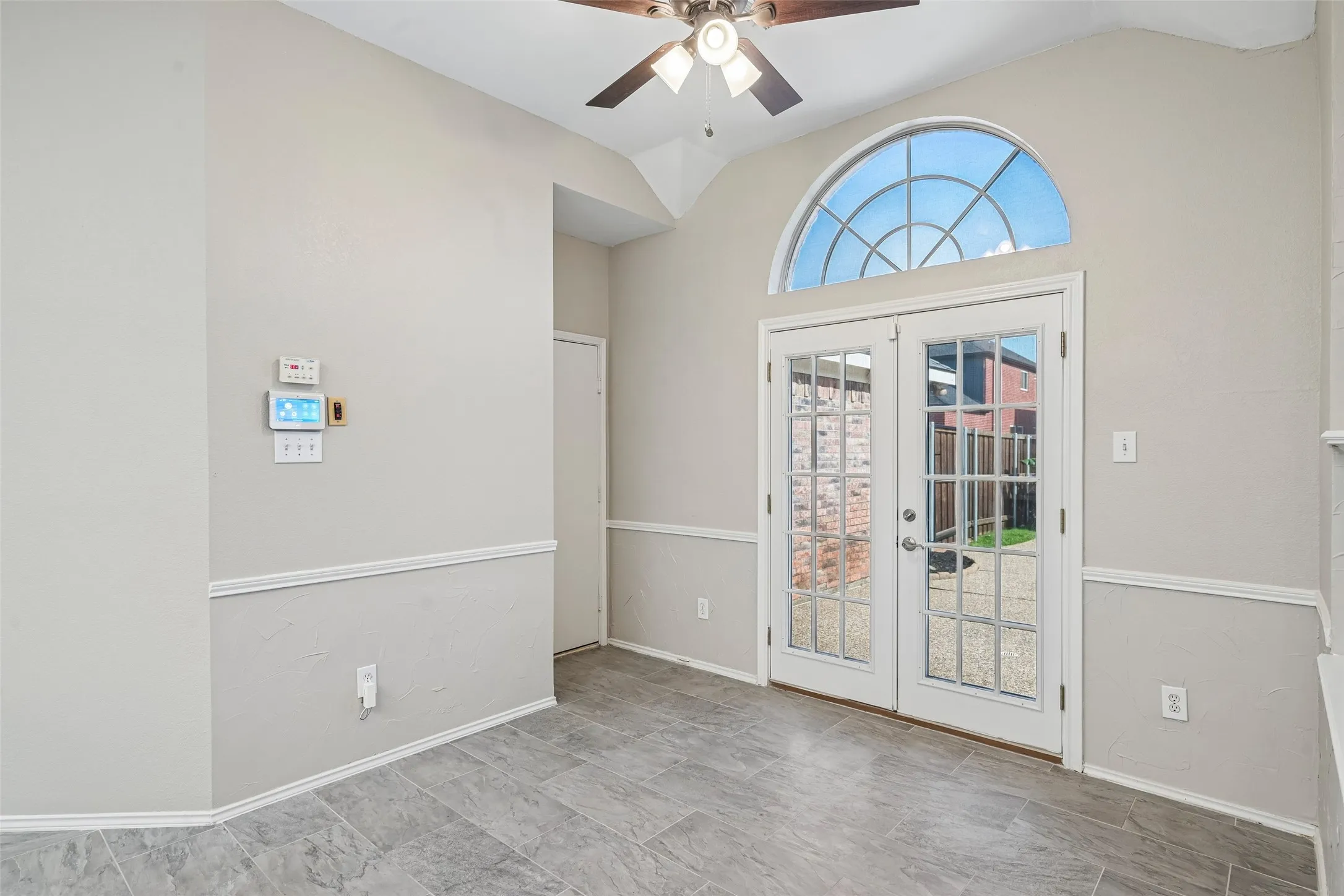 Vaulted ceiling, ceiling fan, French doors with full lites, arched transom window, and tile flooring