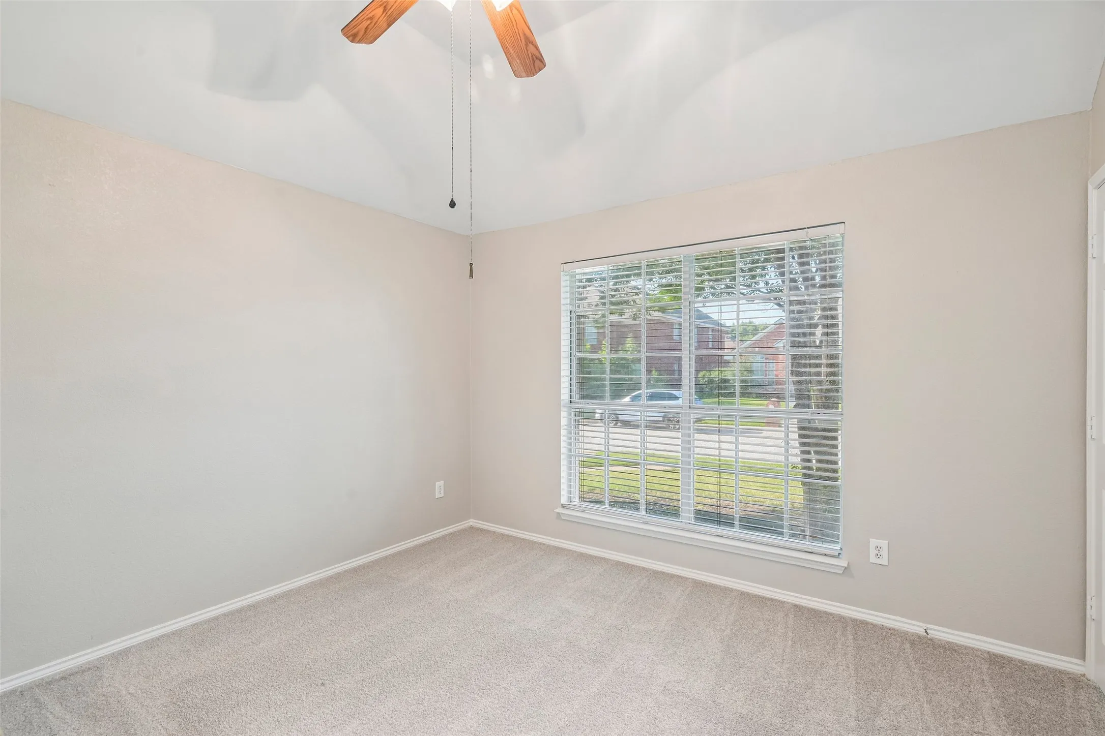 Carpeted flooring, window with blinds, ceiling fan with light fixture, and neutral wall paint