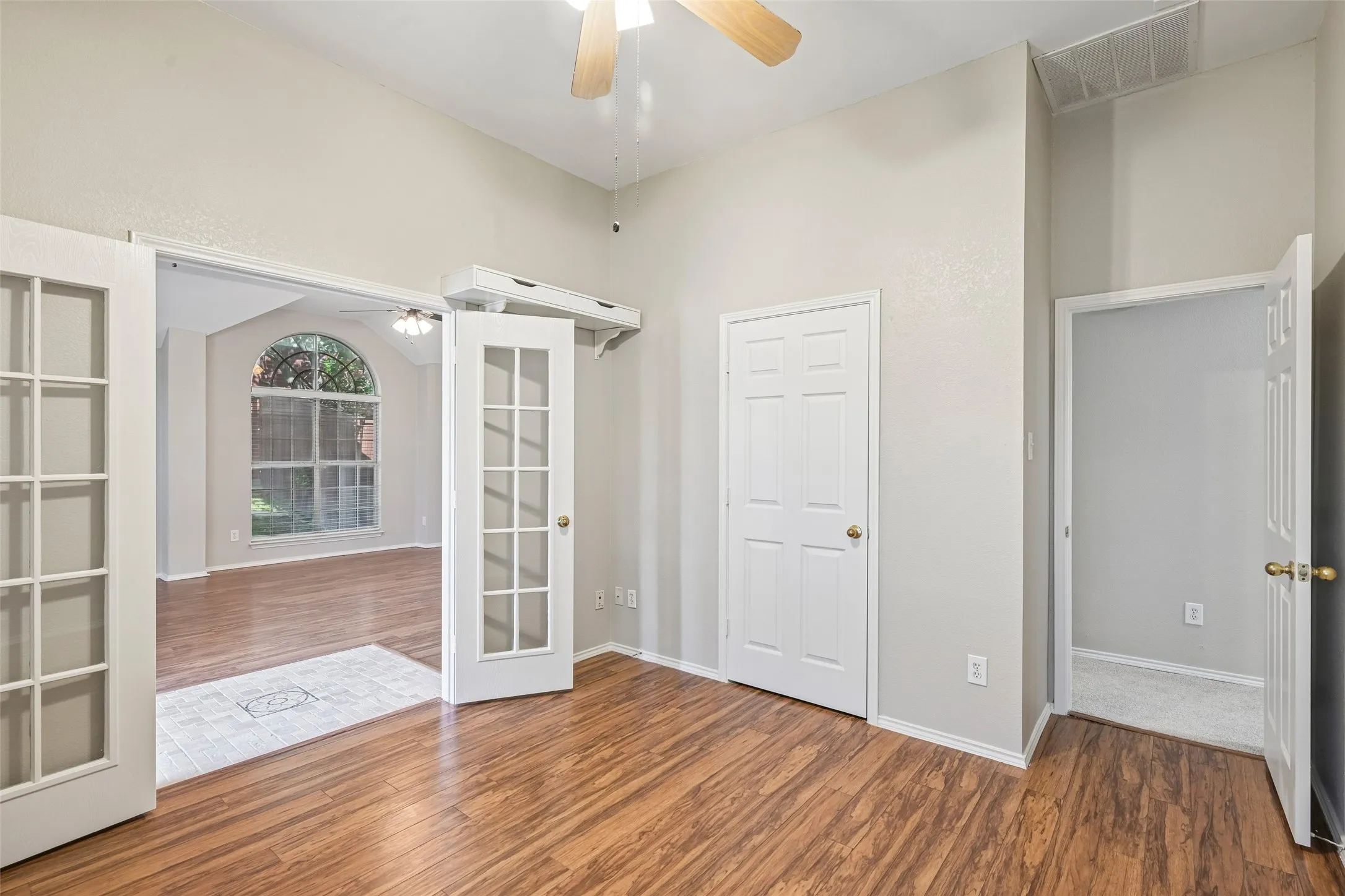 Wood-finish flooring, vaulted ceiling, and white paneled doors