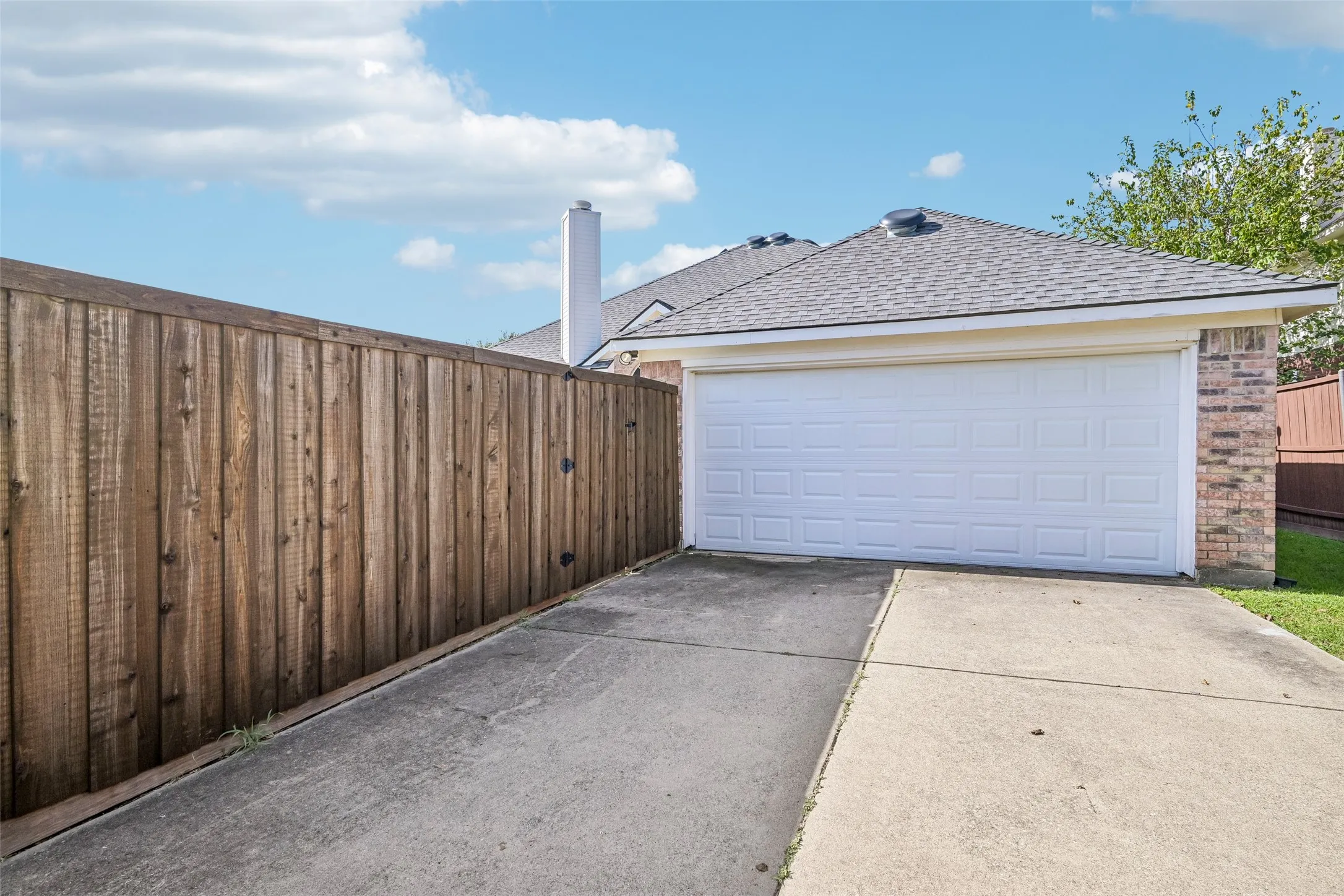 Attached garage with a panel door and brick siding- extra long driveway