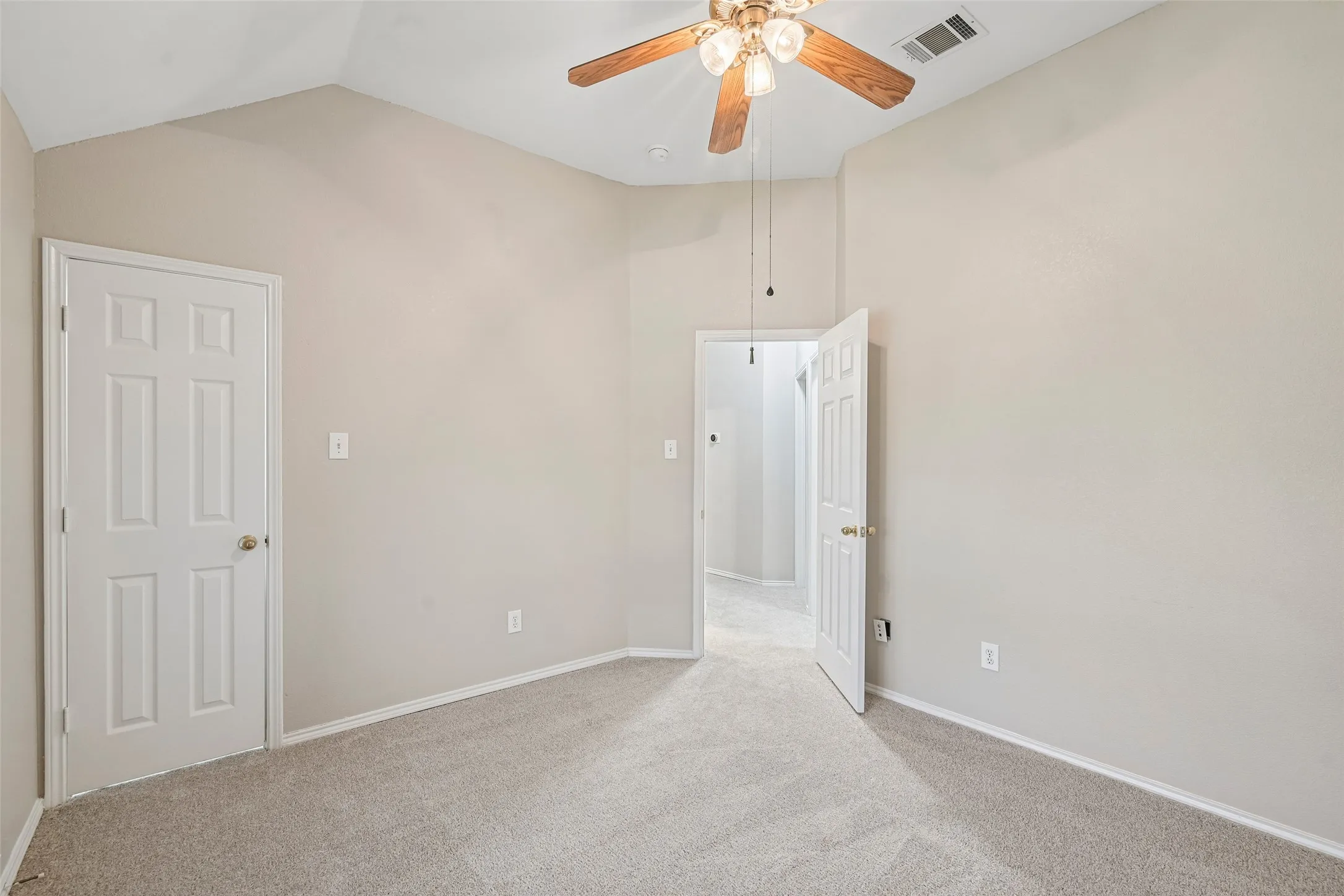 Vaulted ceiling with a ceiling fan, light-colored carpeting, white baseboards, and paneled doors