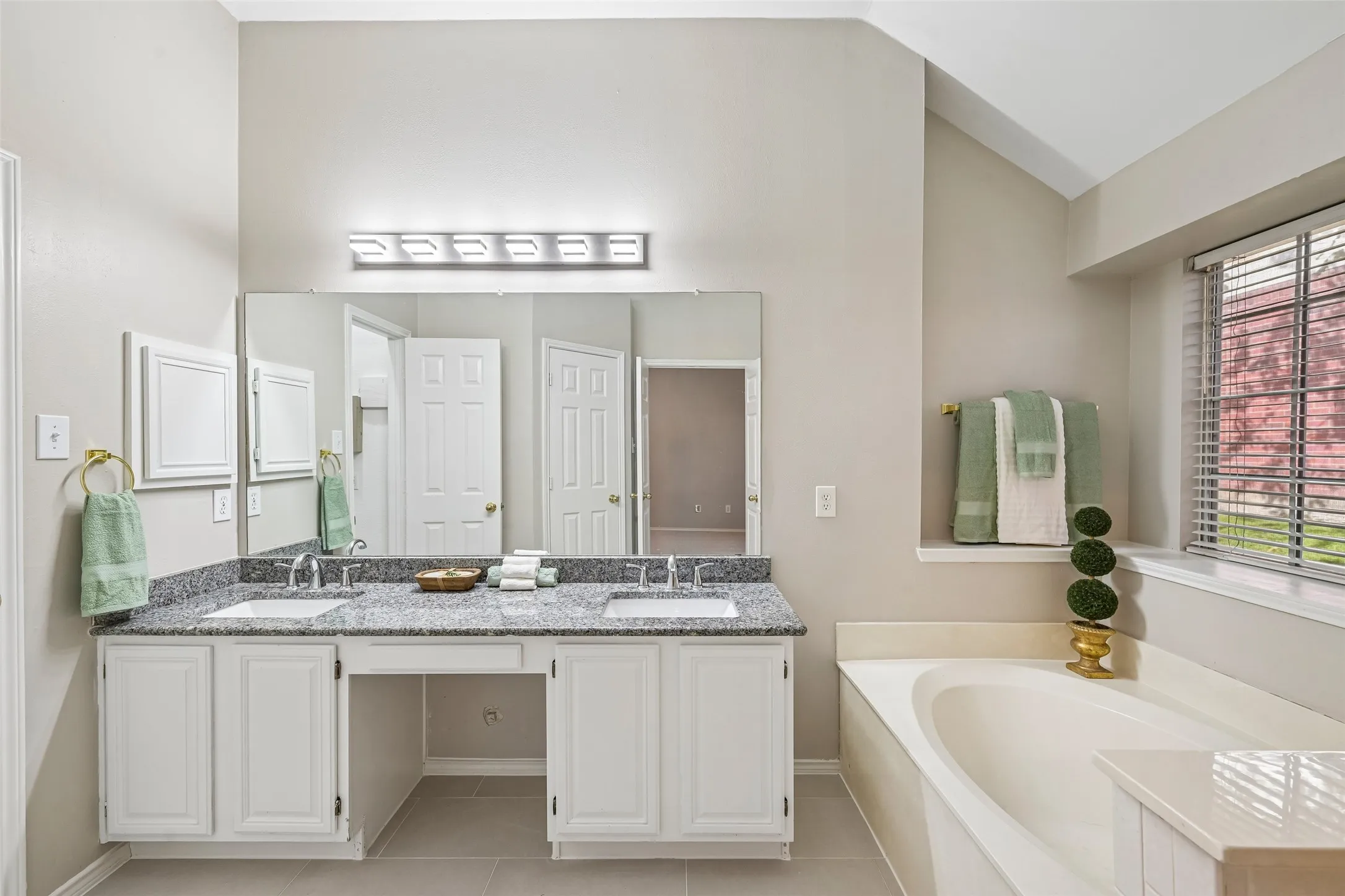Dual vanity with undermount sinks, granite-style countertop, and white cabinetry
