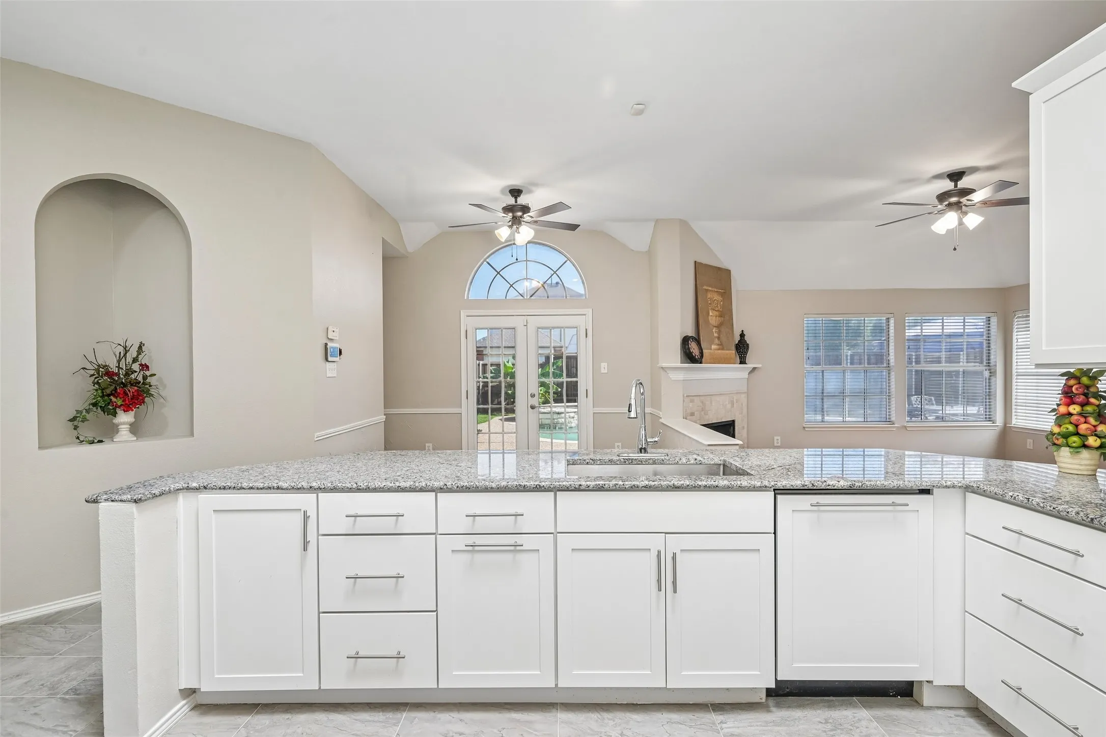 Kitchen island with a stainless steel sink, chrome faucet, and white shaker-style cabinetry
