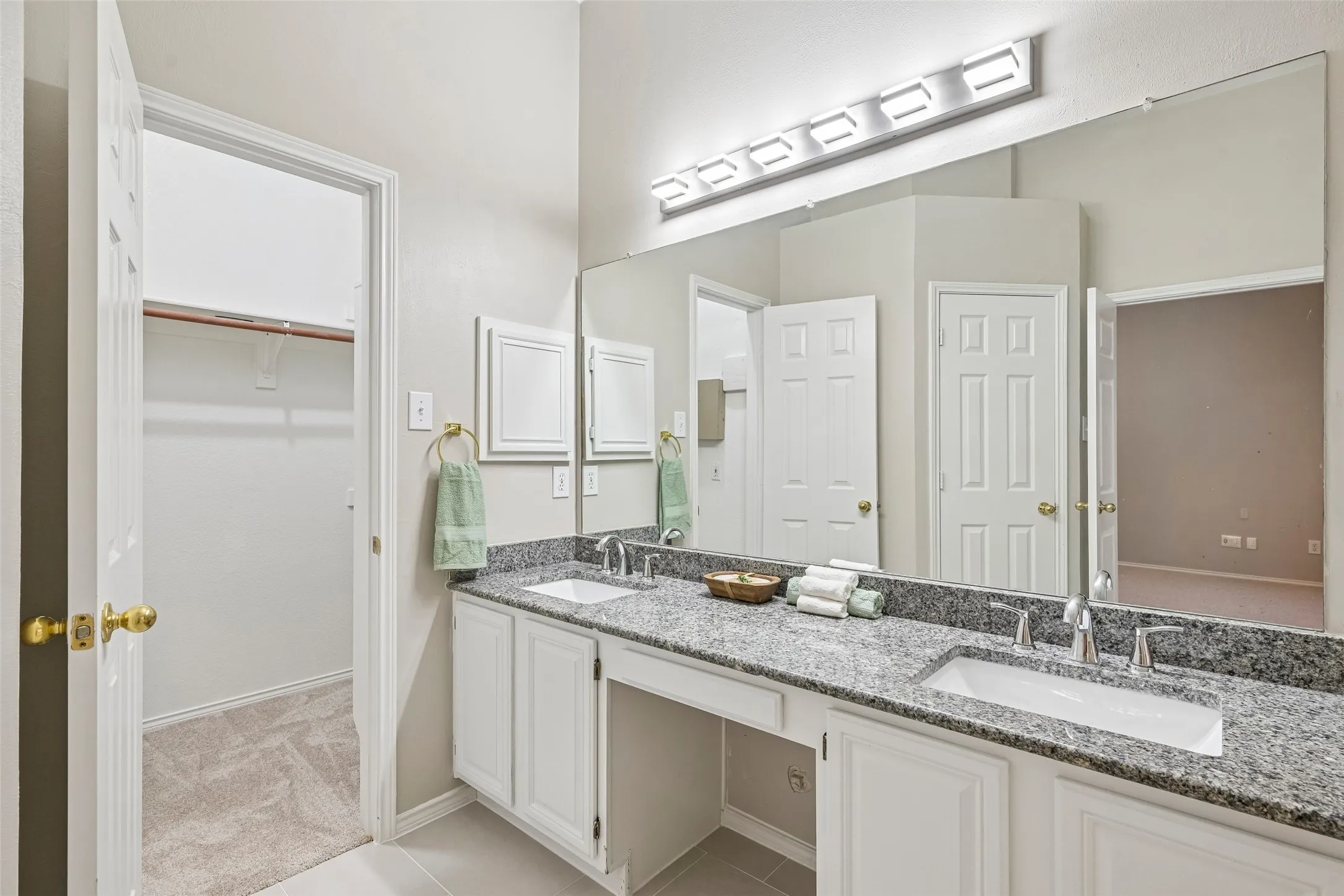 Double vanity with undermount sinks, speckled countertop, and wall-mounted light fixture