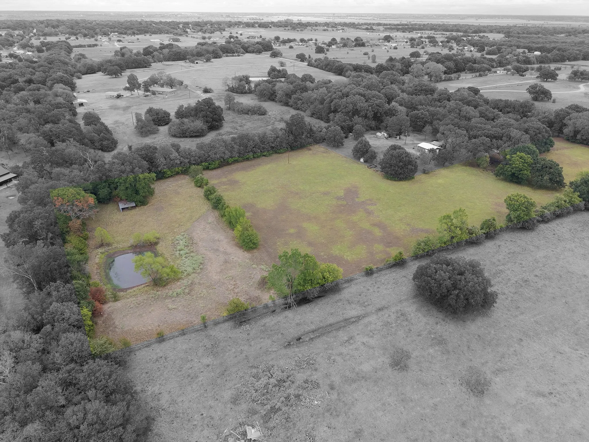 Expansive acreage featuring a pond, mature trees, open fields, and a small outbuilding