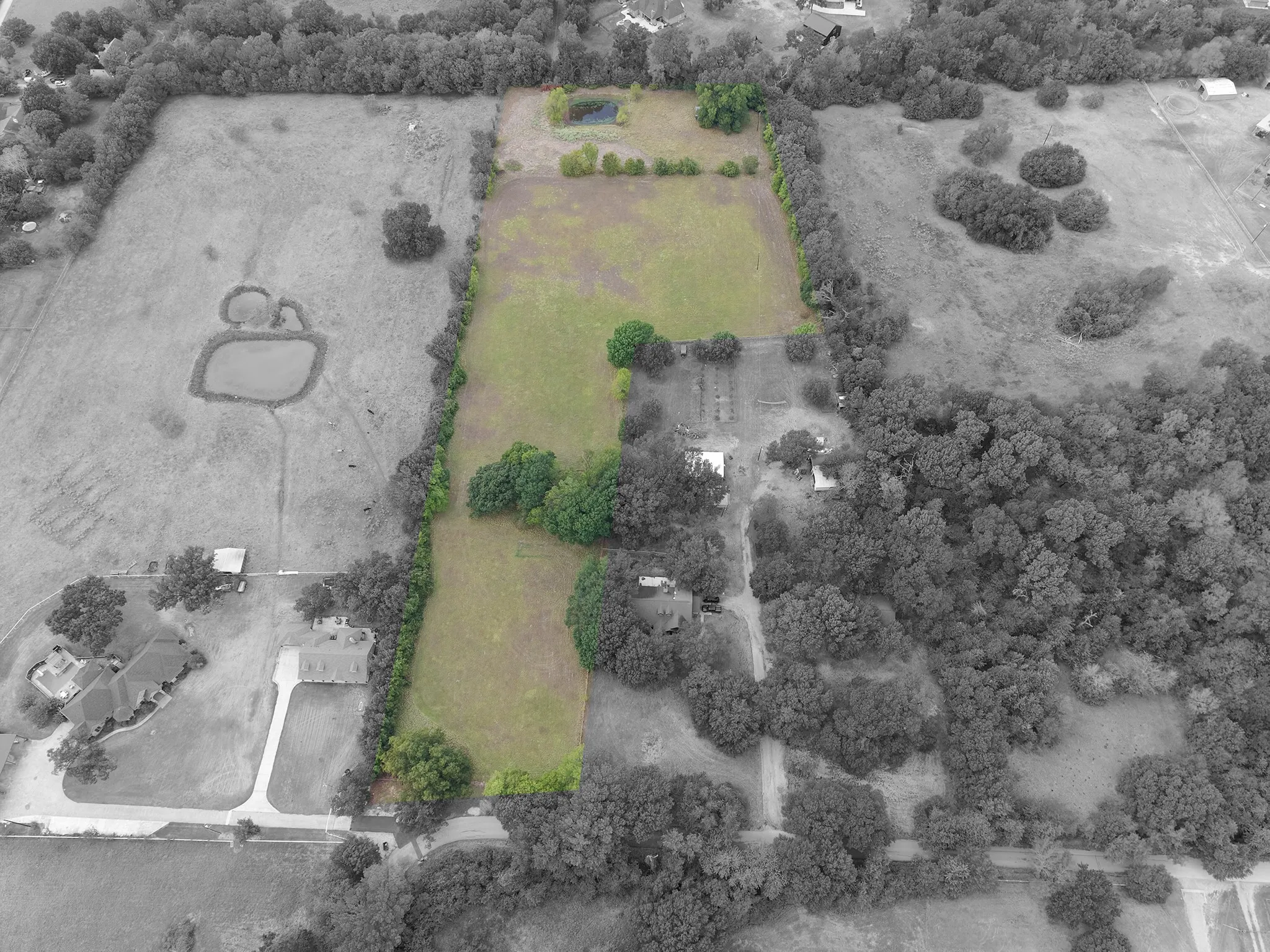 Expansive land with a prominent pond and established tree lines